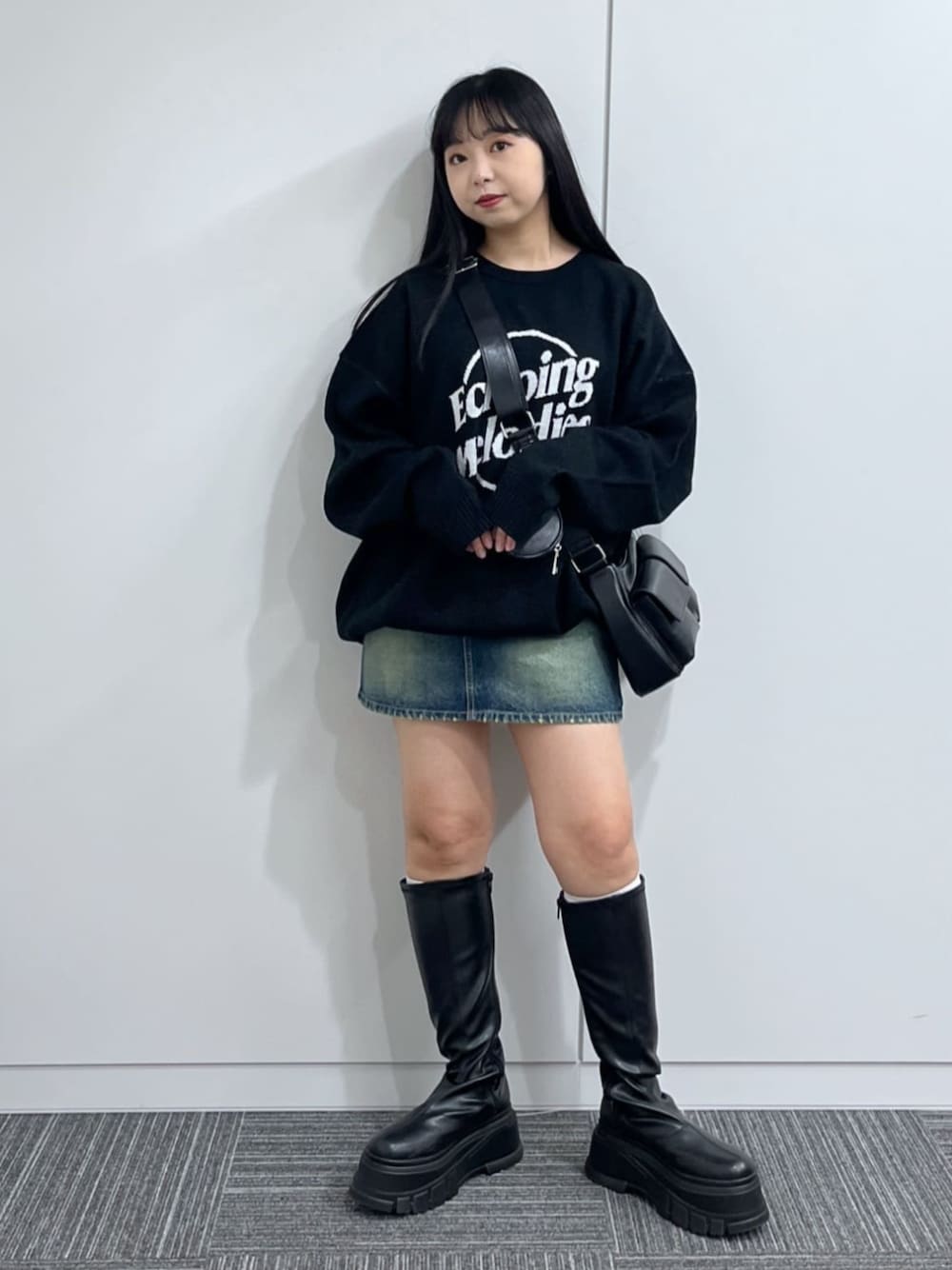 ブラック系のブーツ、その他のニット/セーター、ブルー系のデニムスカートを着用したレディースの春コーディネートの1枚目の写真