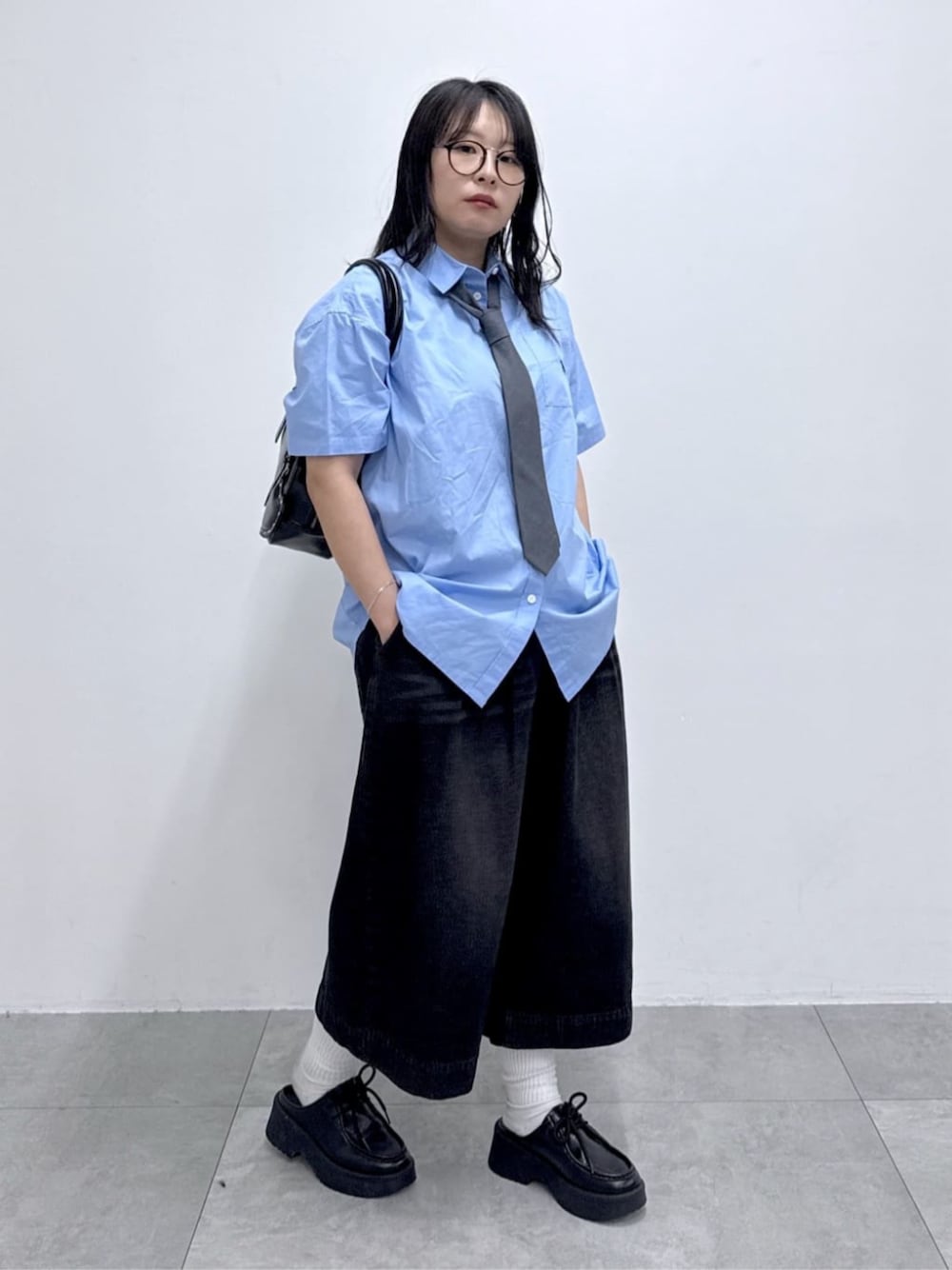 ブルー系のシャツ/ブラウス、ブラック系のハンドバッグ、ブラック系のデニムパンツを着用したレディースの春コーディネートの1枚目の写真