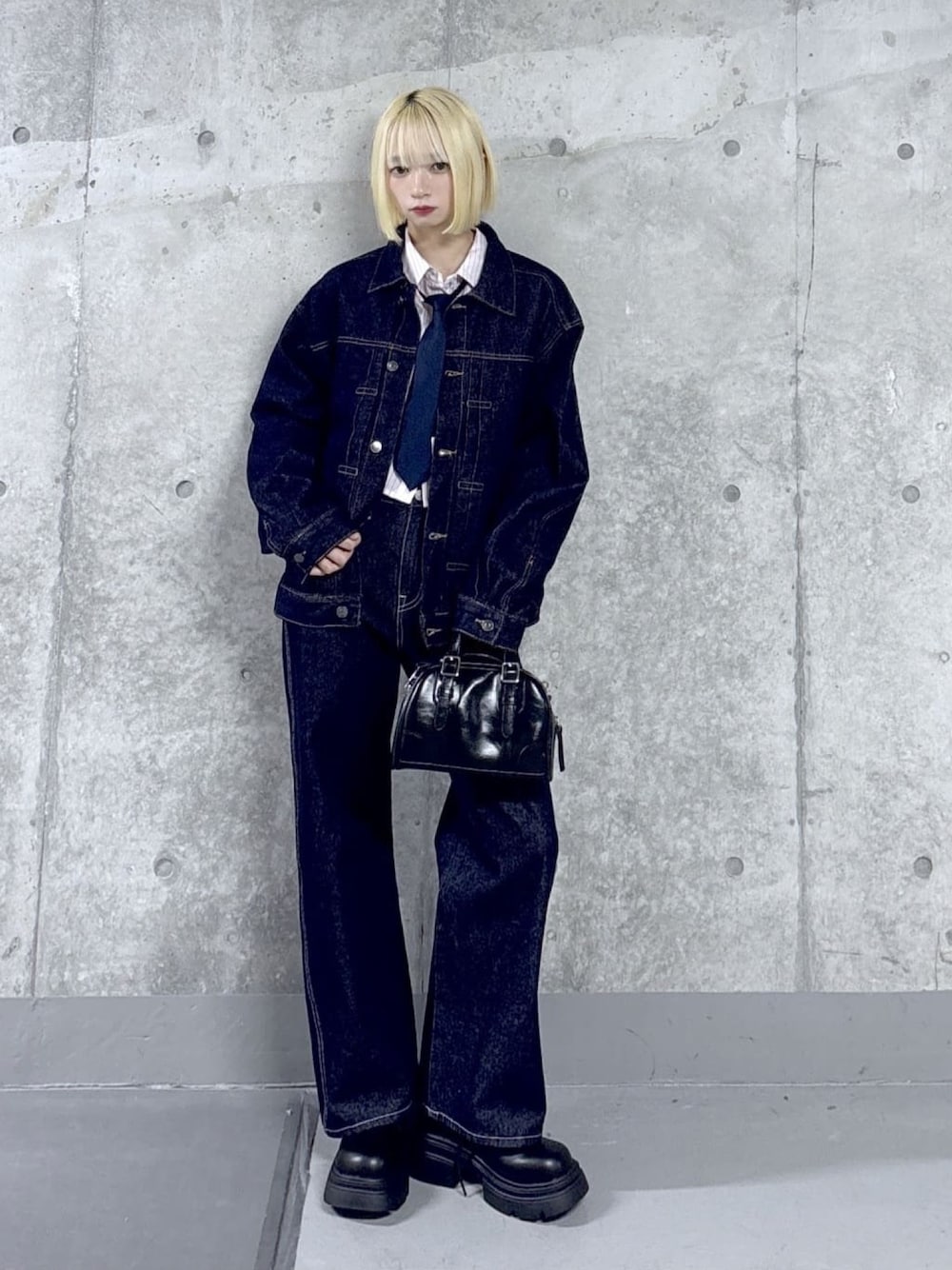 ブルー系のデニムパンツ、ブルー系のデニムジャケット、ブラック系のブーツを着用したレディースの春コーディネートの1枚目の写真