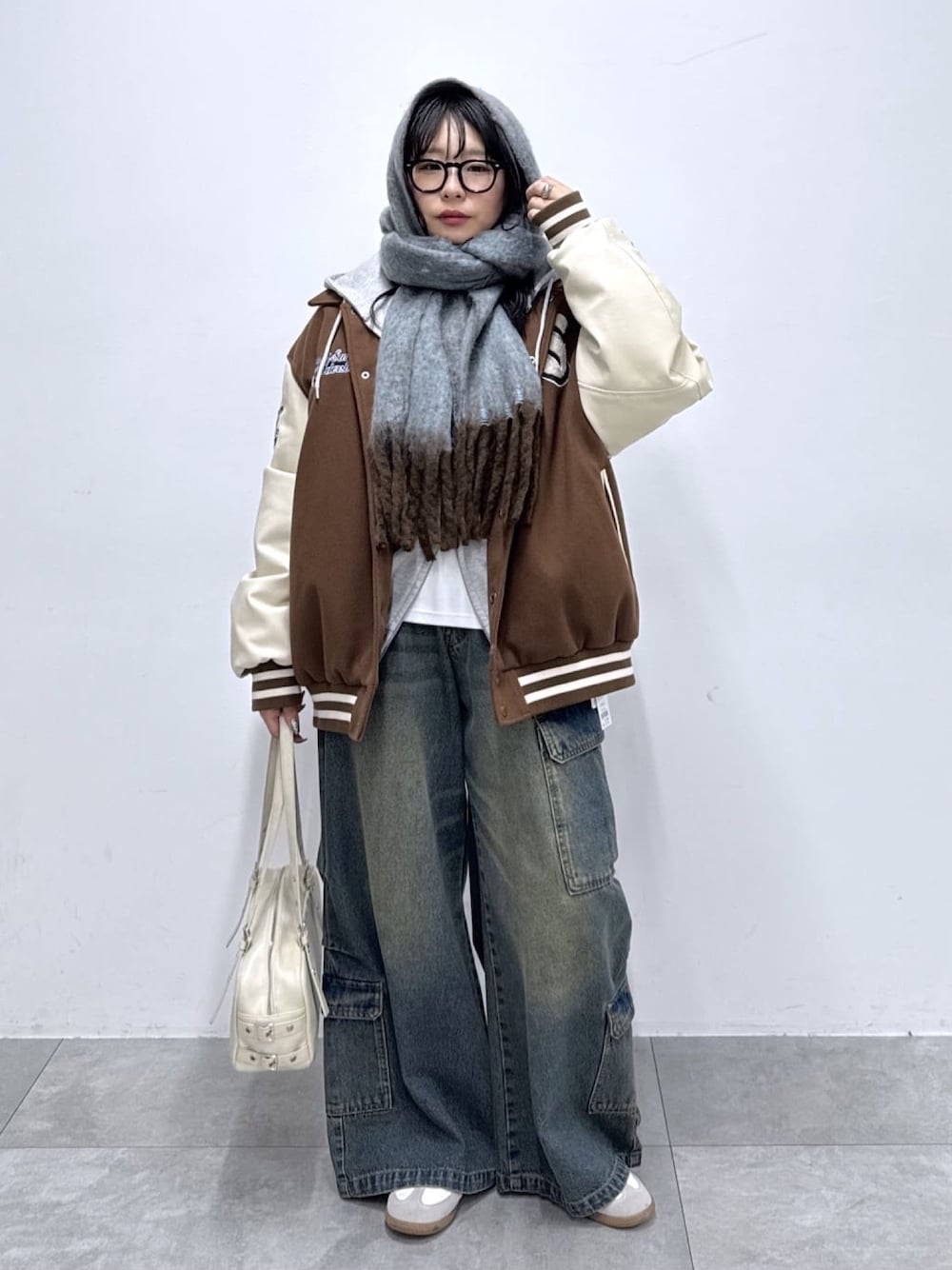 ブラウン系のスタジャン、ブルー系のカーゴパンツ、ベージュ系のボストンバッグを着用したレディースの冬コーディネートの1枚目の写真