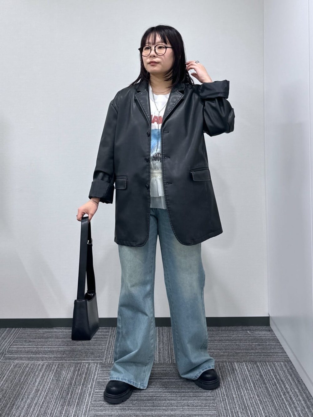 ブラック系のショルダーバッグ、ブルー系のデニムパンツ、ブラック系のテーラードジャケットを着用したレディースの春コーディネートの1枚目の写真