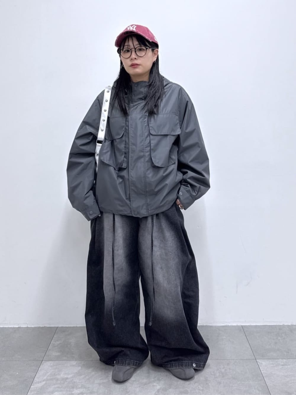 ブラック系のデニムパンツ、グレー系のマウンテンパーカー、シルバー系のハンドバッグを着用したレディースの春コーディネートの1枚目の写真