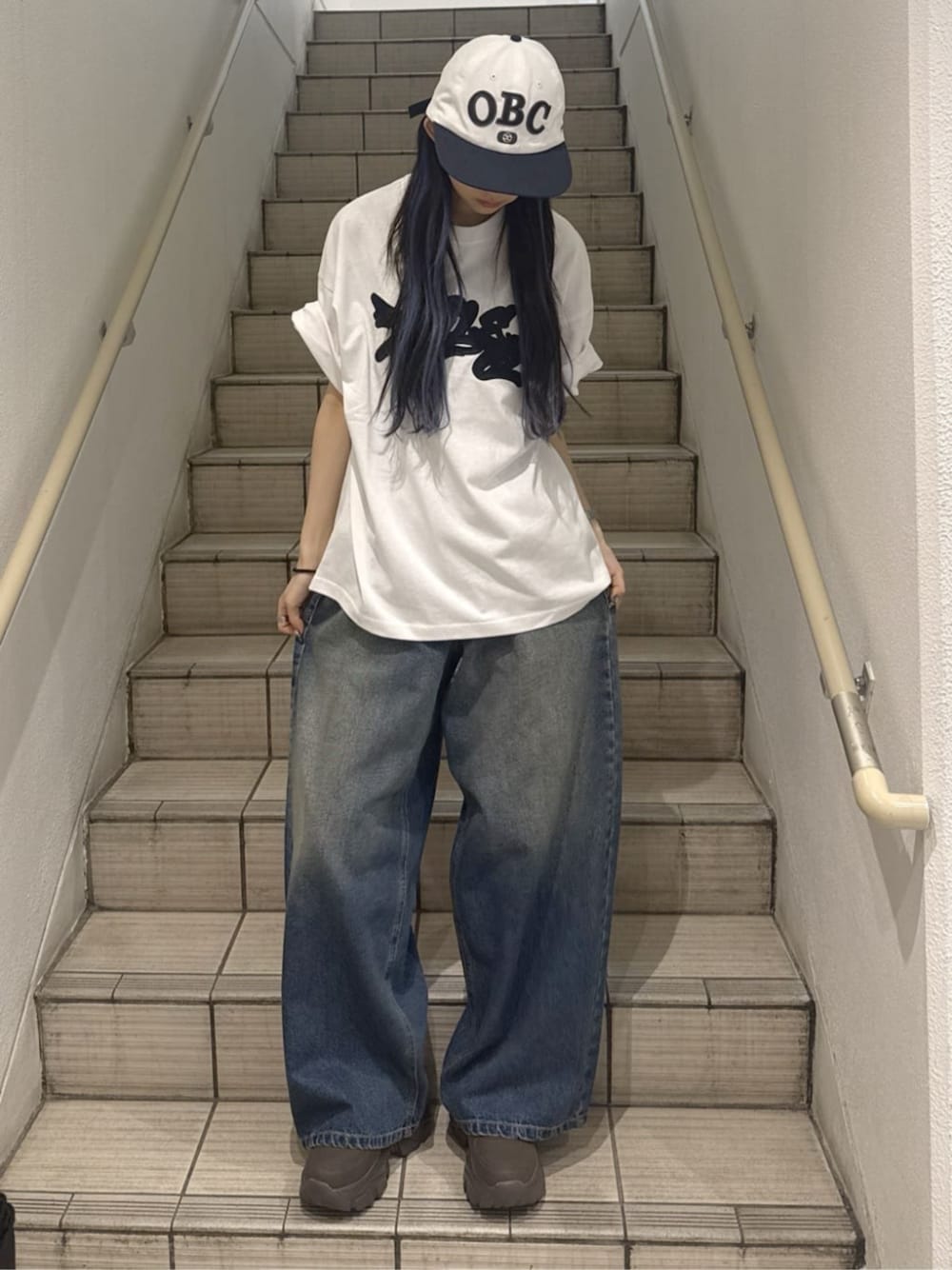 ブラウン系のスニーカー、ブルー系のデニムパンツ、ホワイト系のTシャツ/カットソーを着用したレディースの春コーディネートの1枚目の写真
