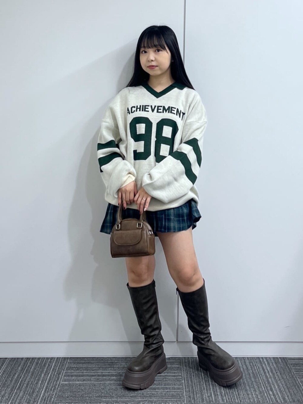 ブラウン系のショルダーバッグ、ブラウン系のブーツ、グリーン系のニット/セーターを着用したレディースの秋コーディネートの1枚目の写真