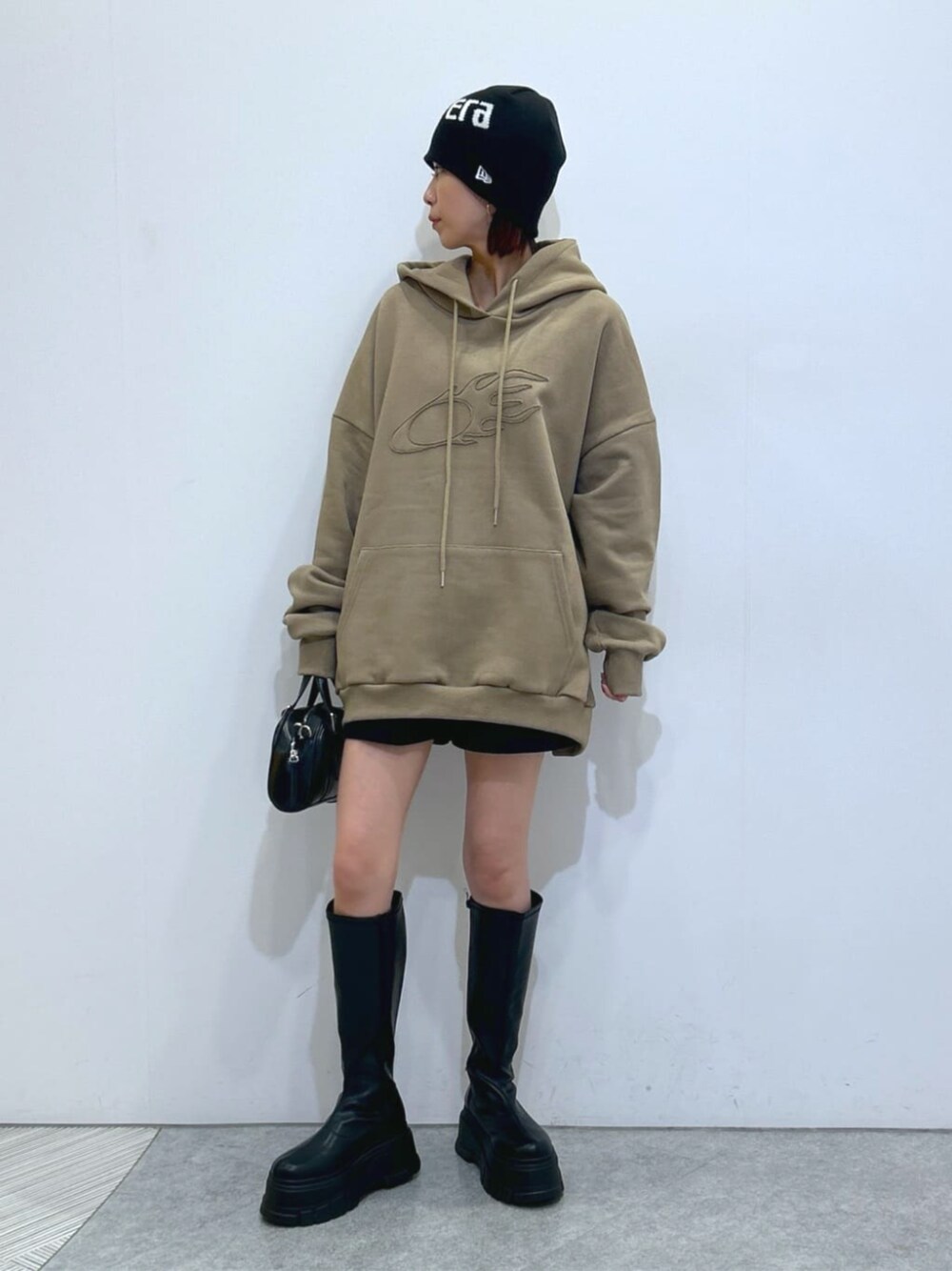 ブラック系のブーツ、ブラック系のデニムパンツ、ベージュ系のパーカーを着用したレディースの秋コーディネートの1枚目の写真