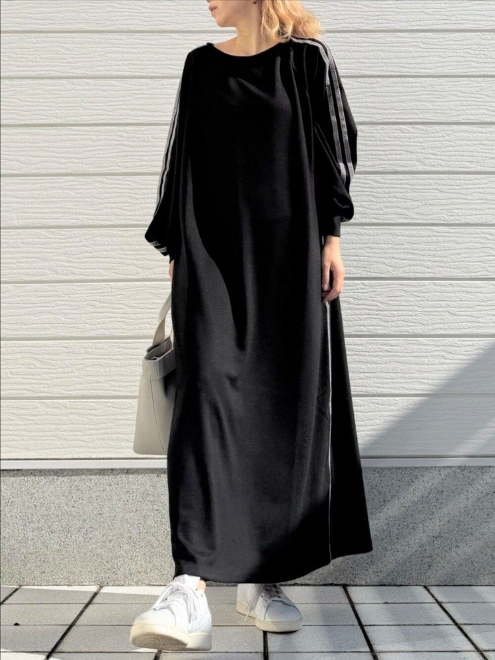 ホワイト系のスニーカー、ブラック系のワンピース、グレー系のトートバッグを着用したレディースの秋コーディネートの1枚目の写真