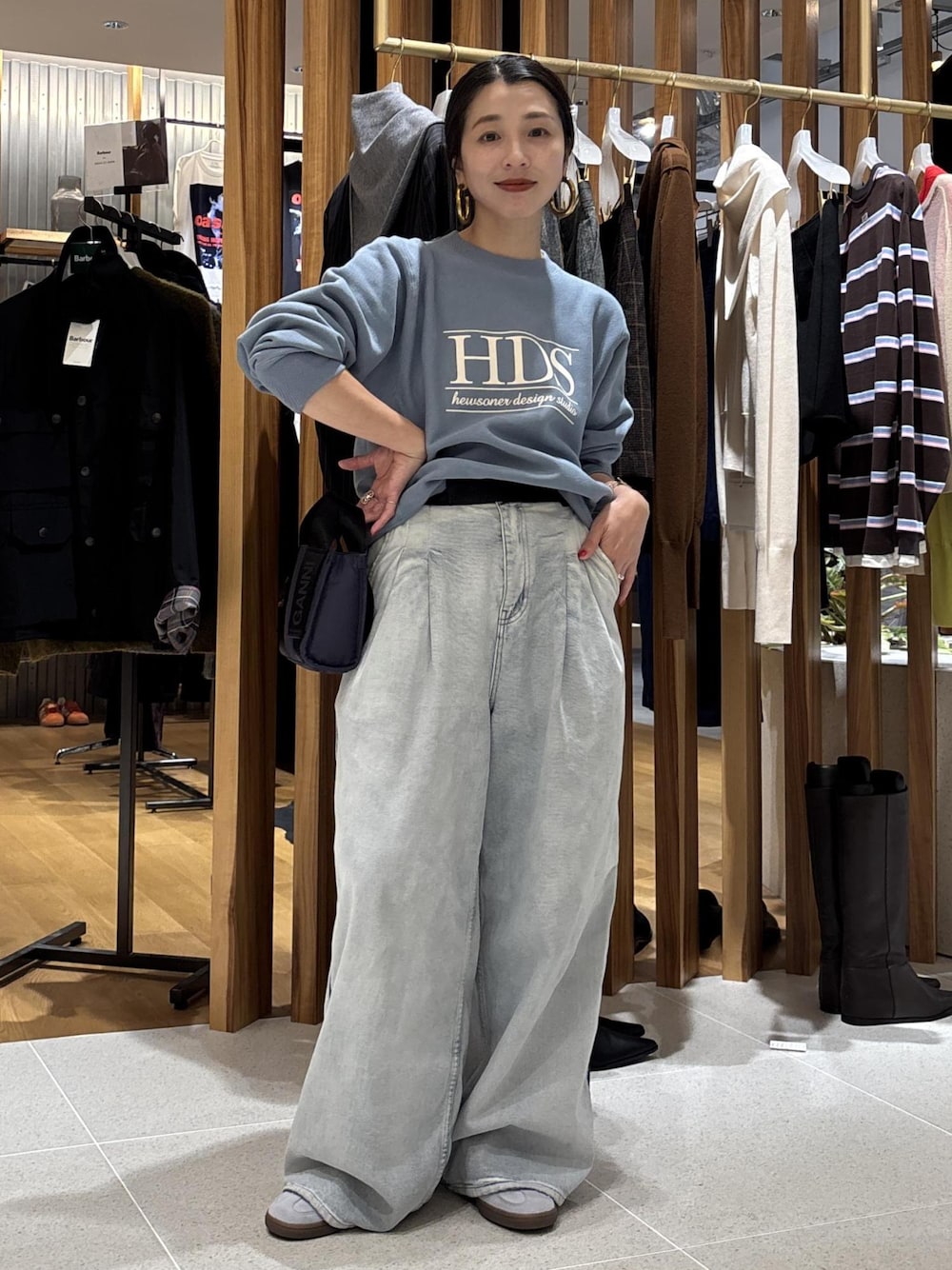 ブルー系のデニムパンツ、ブルー系のショルダーバッグ、ブルー系のスウェットを着用したレディースの秋コーディネートの1枚目の写真