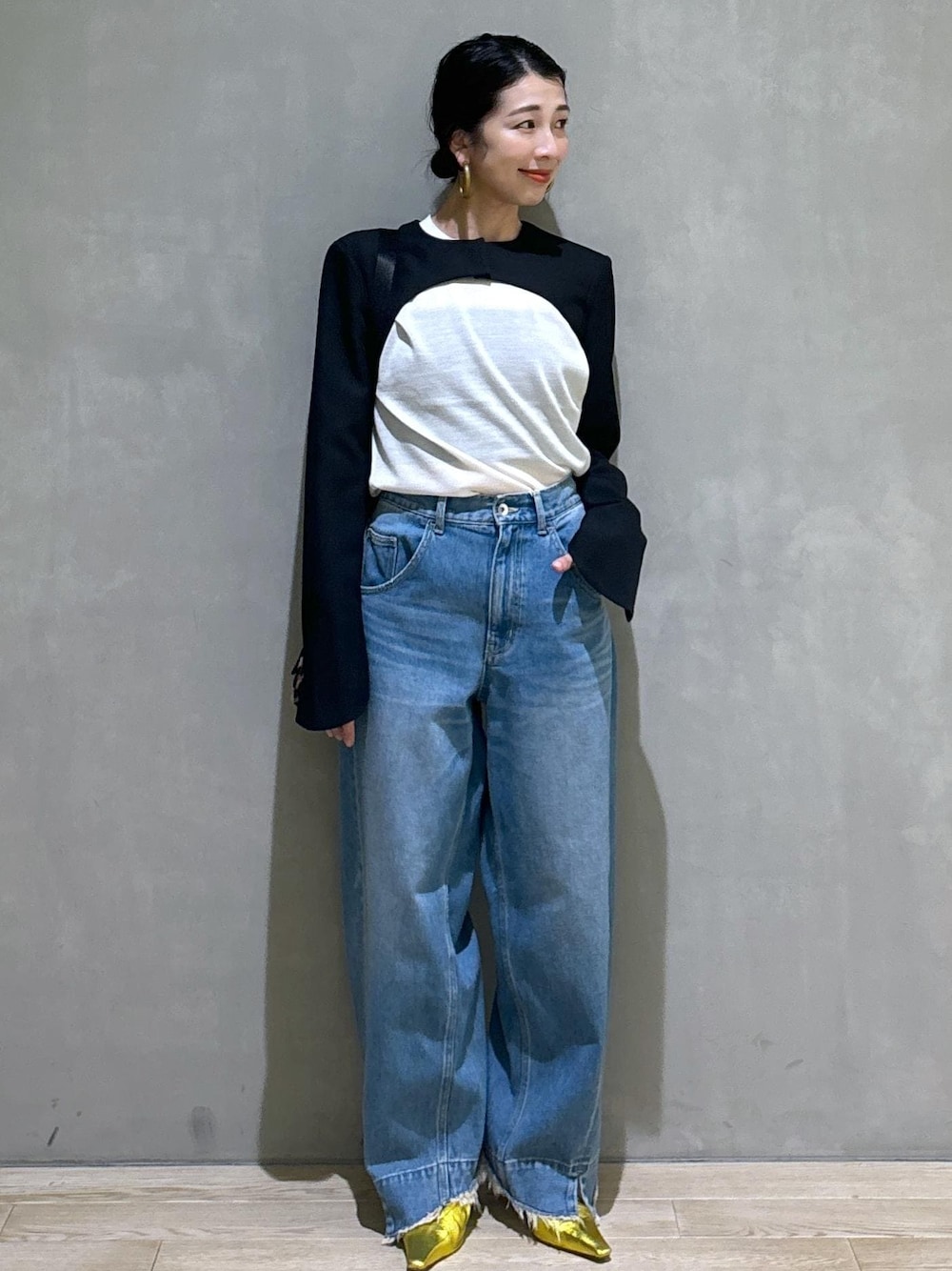 ブルー系のデニムパンツ、ゴールド系のパンプス、ブラック系のノーカラージャケットを着用したレディースの秋コーディネートの1枚目の写真