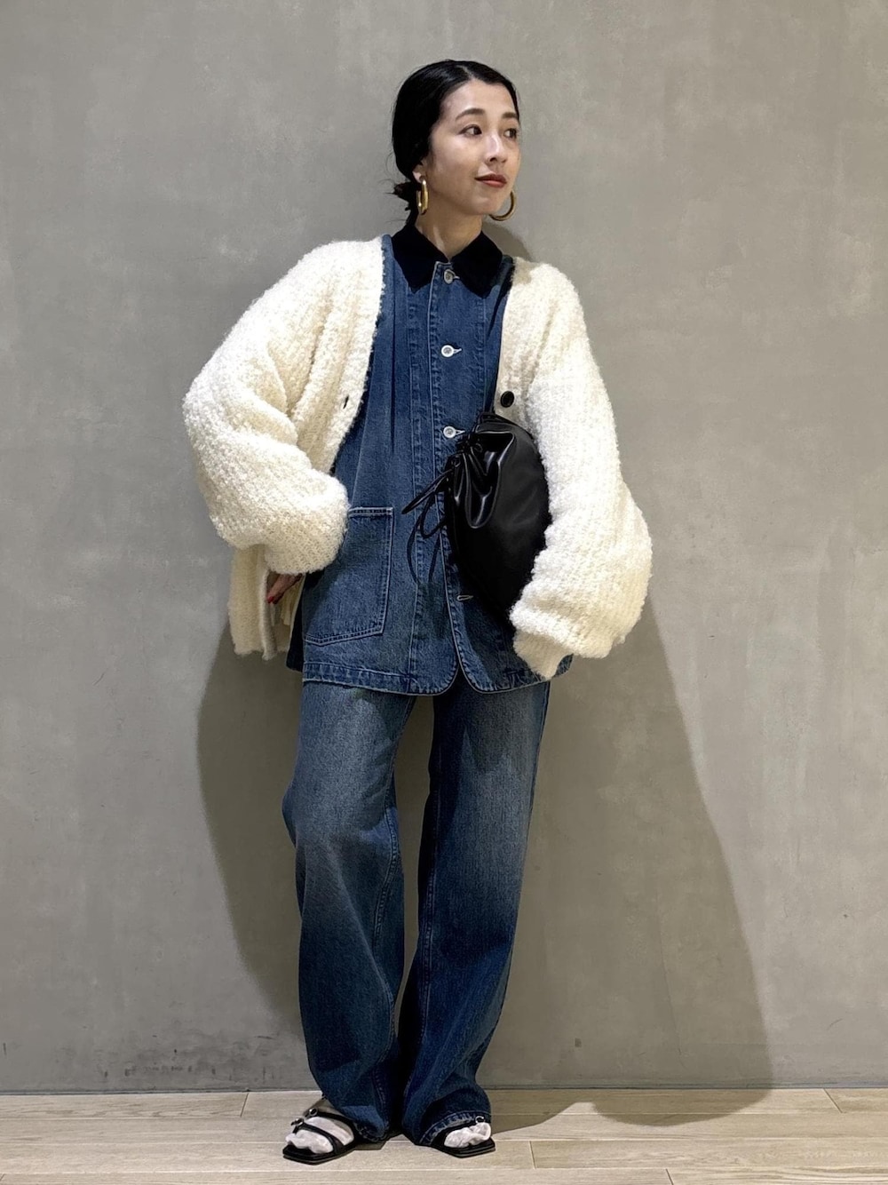 ブラック系のショルダーバッグ、ブルー系のデニムパンツ、ブルー系のカバーオールを着用したレディースの秋コーディネートの1枚目の写真