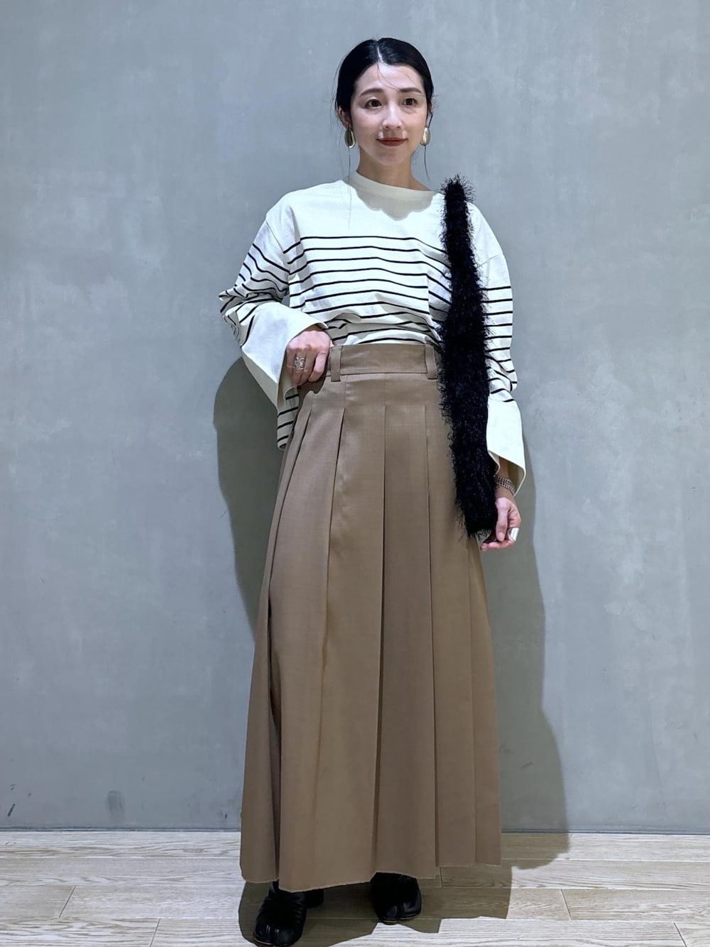 ベージュ系のスカート、ホワイト系のTシャツ/カットソー、ブラック系のハンドバッグを着用したレディースの夏コーディネートの1枚目の写真