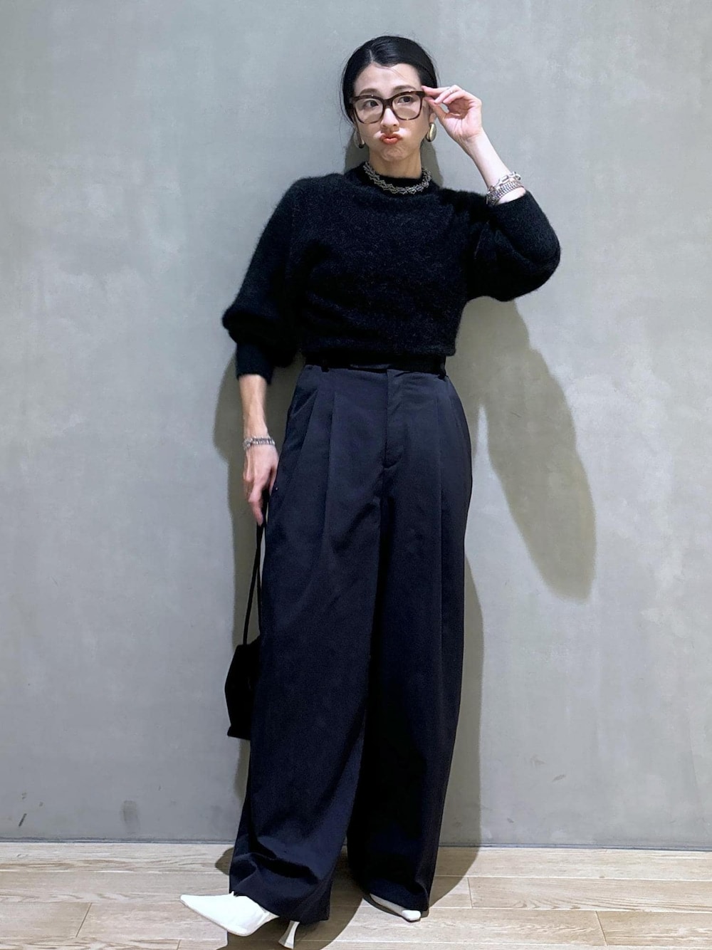 ホワイト系のパンプス、ブラック系のスラックス、グレー系のニット/セーターを着用したレディースの秋コーディネートの1枚目の写真