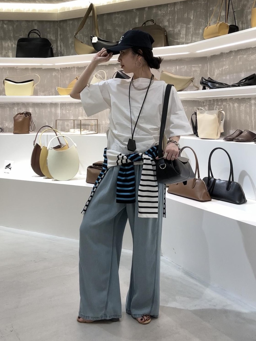ブルー系のデニムパンツ、ブラック系のショルダーバッグ、ブルー系のTシャツ/カットソーを着用したレディースの春コーディネートの1枚目の写真