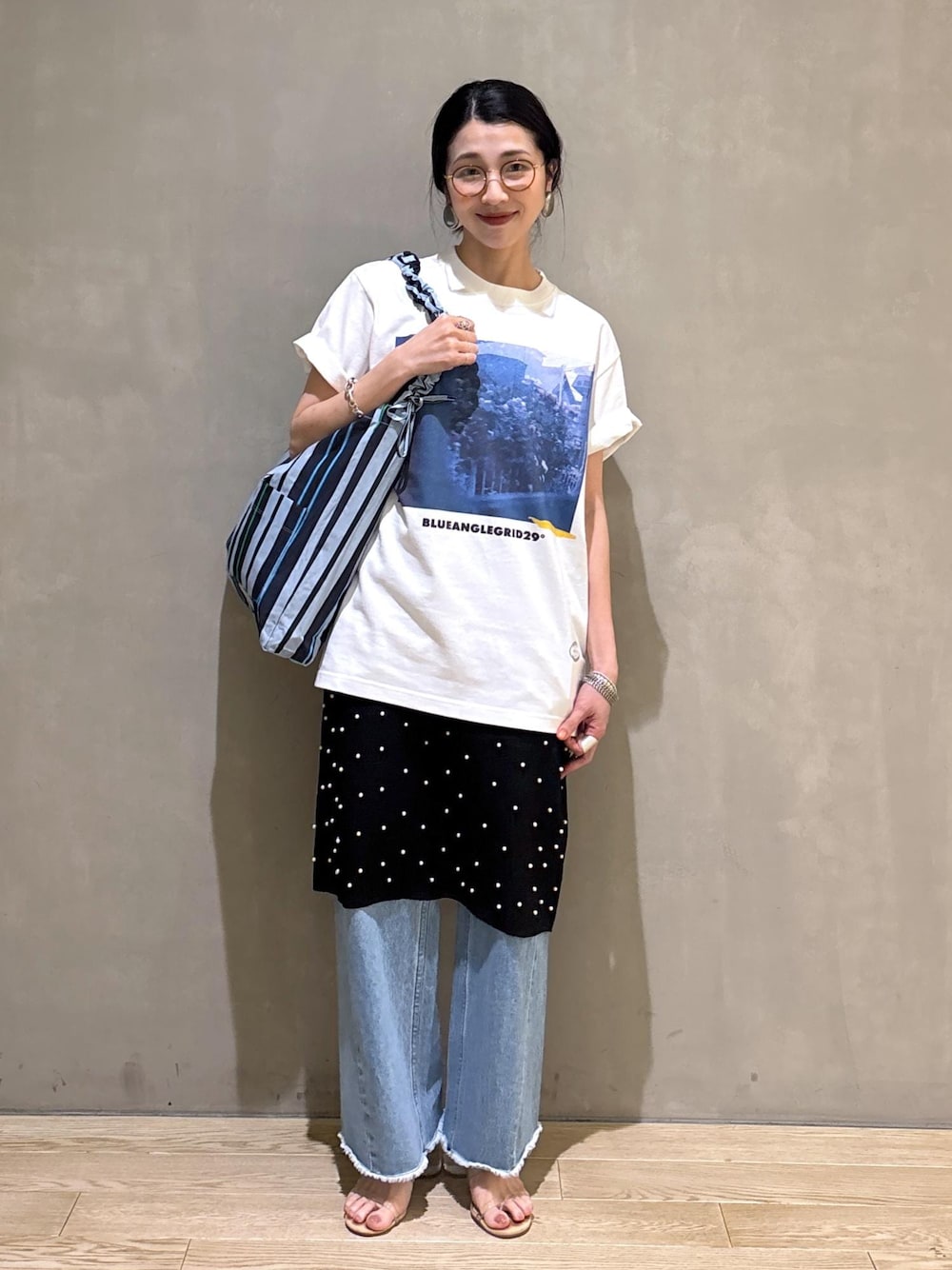 ブルー系のデニムパンツ、ブルー系のショルダーバッグ、ホワイト系のTシャツ/カットソーを着用したレディースの春コーディネートの1枚目の写真