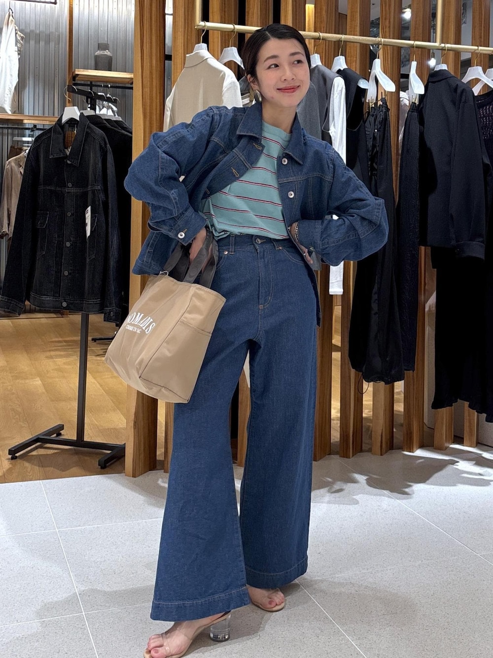 ベージュ系のハンドバッグ、ブルー系のTシャツ/カットソー、ブルー系のブルゾンを着用したレディースの冬コーディネートの1枚目の写真