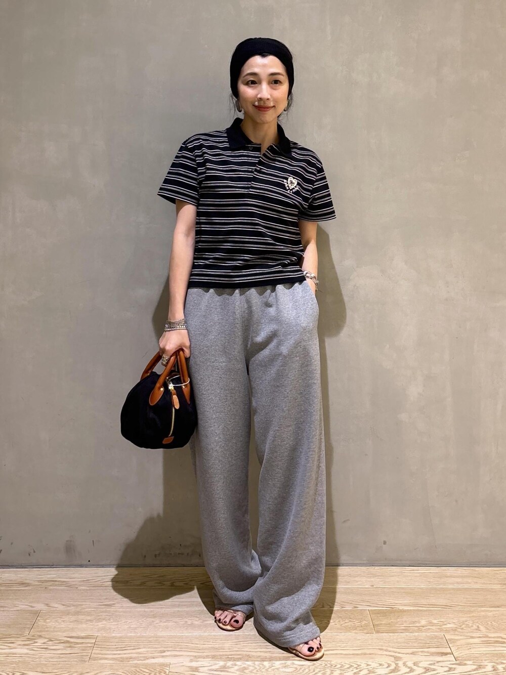グレー系のスウェットパンツ、ブラック系のポロシャツを着用したレディースの夏コーディネートの1枚目の写真