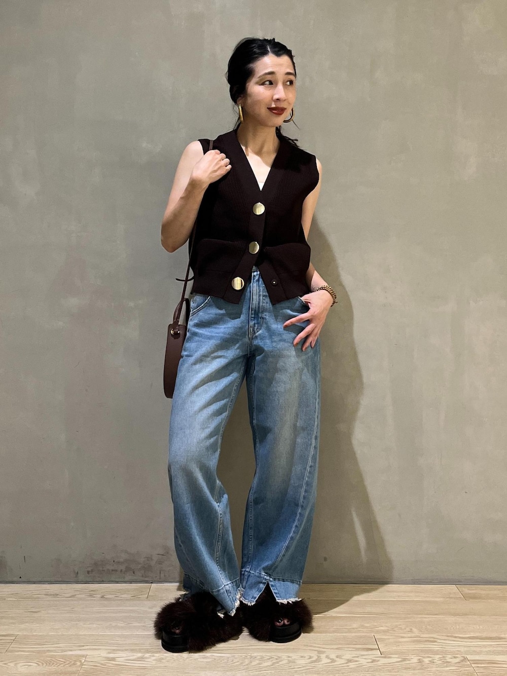 ブルー系のデニムパンツ、ブラウン系のサンダル、ブラウン系のベストを着用したレディースの夏コーディネートの1枚目の写真