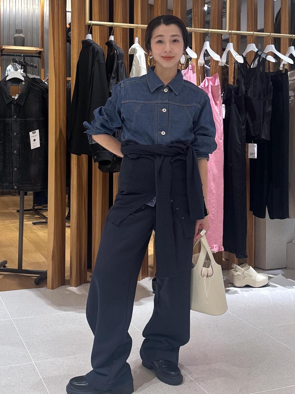 ブラック系のローファー、ホワイト系のハンドバッグ、ブルー系のブルゾンを着用したレディースの春コーディネートの1枚目の写真