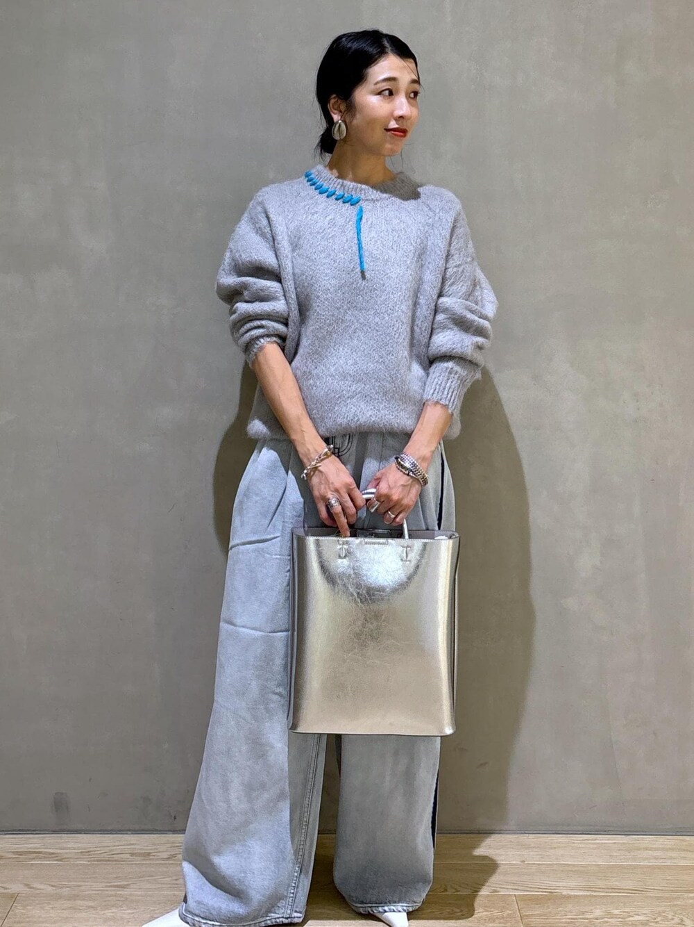 ホワイト系のパンプス、シルバー系のトートバッグ、ブルー系のその他パンツを着用したレディースの秋コーディネートの1枚目の写真