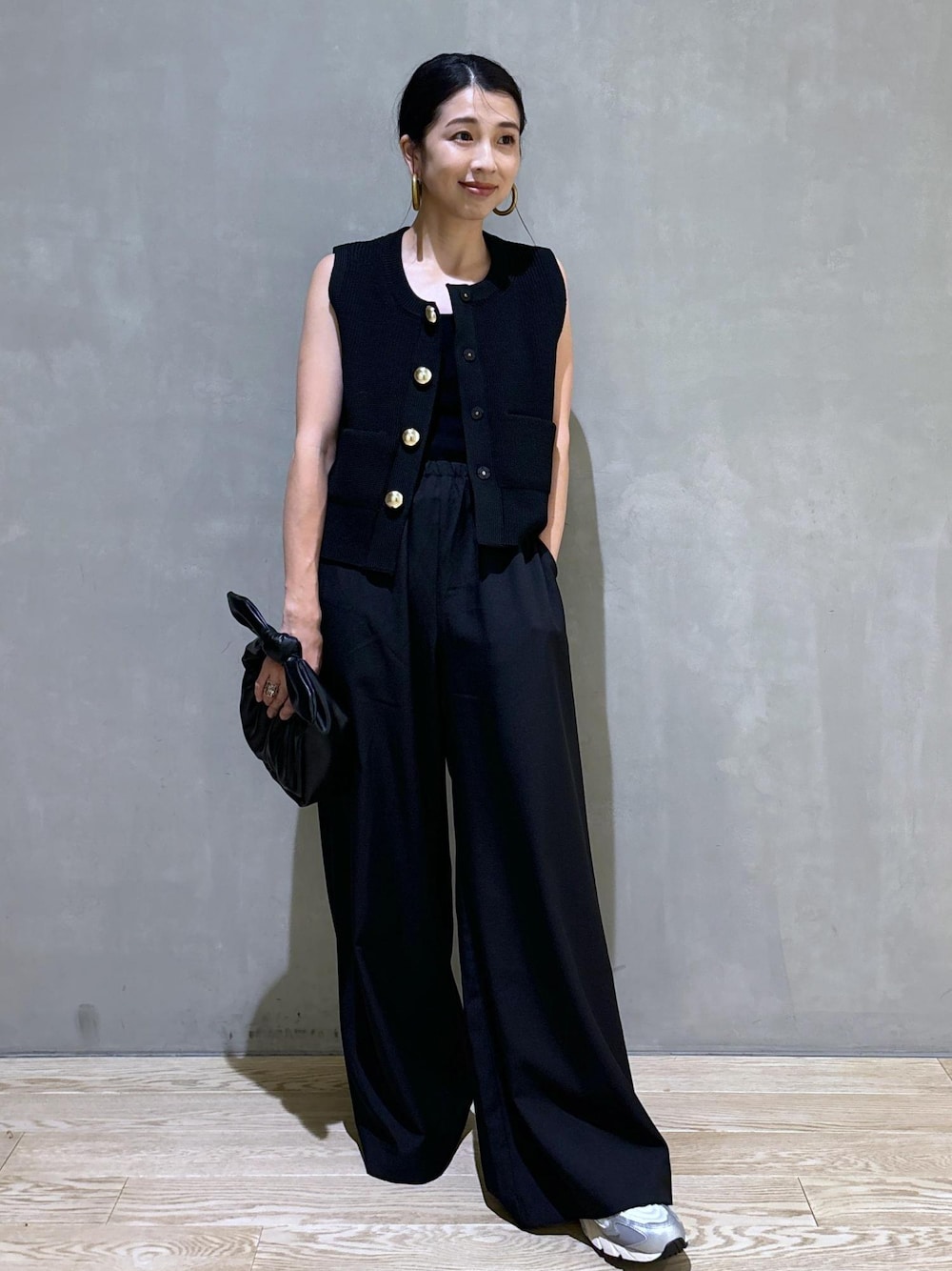 シルバー系のスニーカー、ブラック系のニット/セーター、ブラック系のショルダーバッグを着用したレディースの夏コーディネートの1枚目の写真