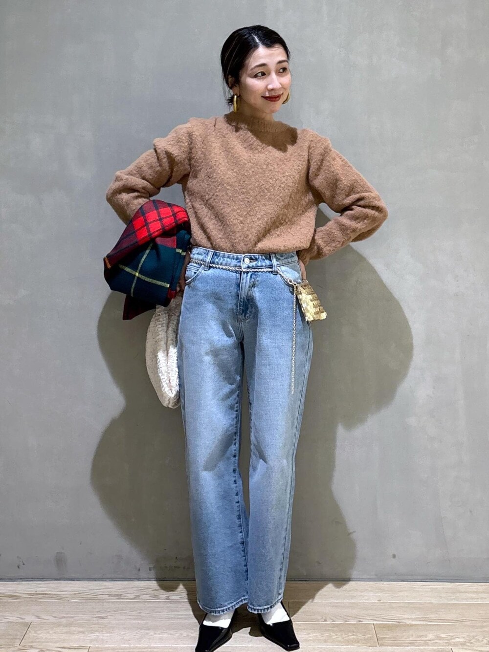 ホワイト系のハンドバッグ、ゴールド系のショルダーバッグ、ブルー系のデニムパンツを着用したレディースの冬コーディネートの1枚目の写真