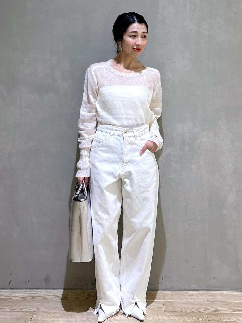 ホワイト系のパンプス、シルバー系のトートバッグ、ホワイト系のデニムパンツを着用したレディースの冬コーディネートの1枚目の写真