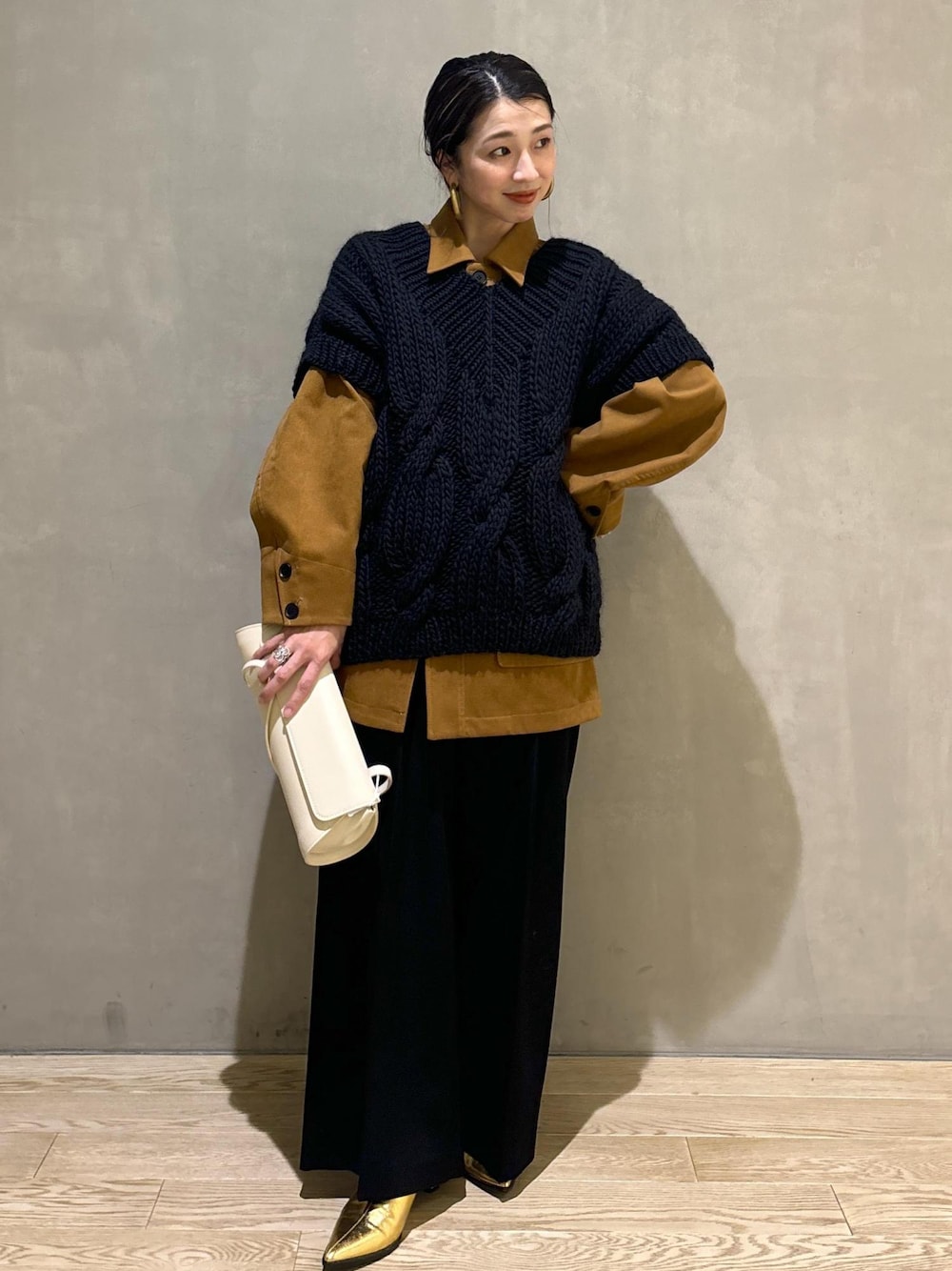 ブラック系のニット/セーター、ゴールド系のブーツ、イエロー系のブルゾンを着用したレディースの秋コーディネートの1枚目の写真