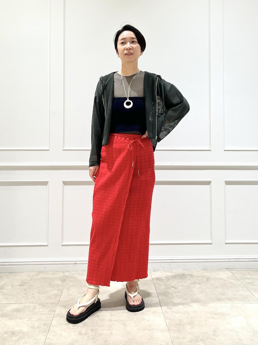 ホワイト系のサンダル、レッド系のスカート、グリーン系のTシャツ/カットソーを着用したレディースの春コーディネートの1枚目の写真