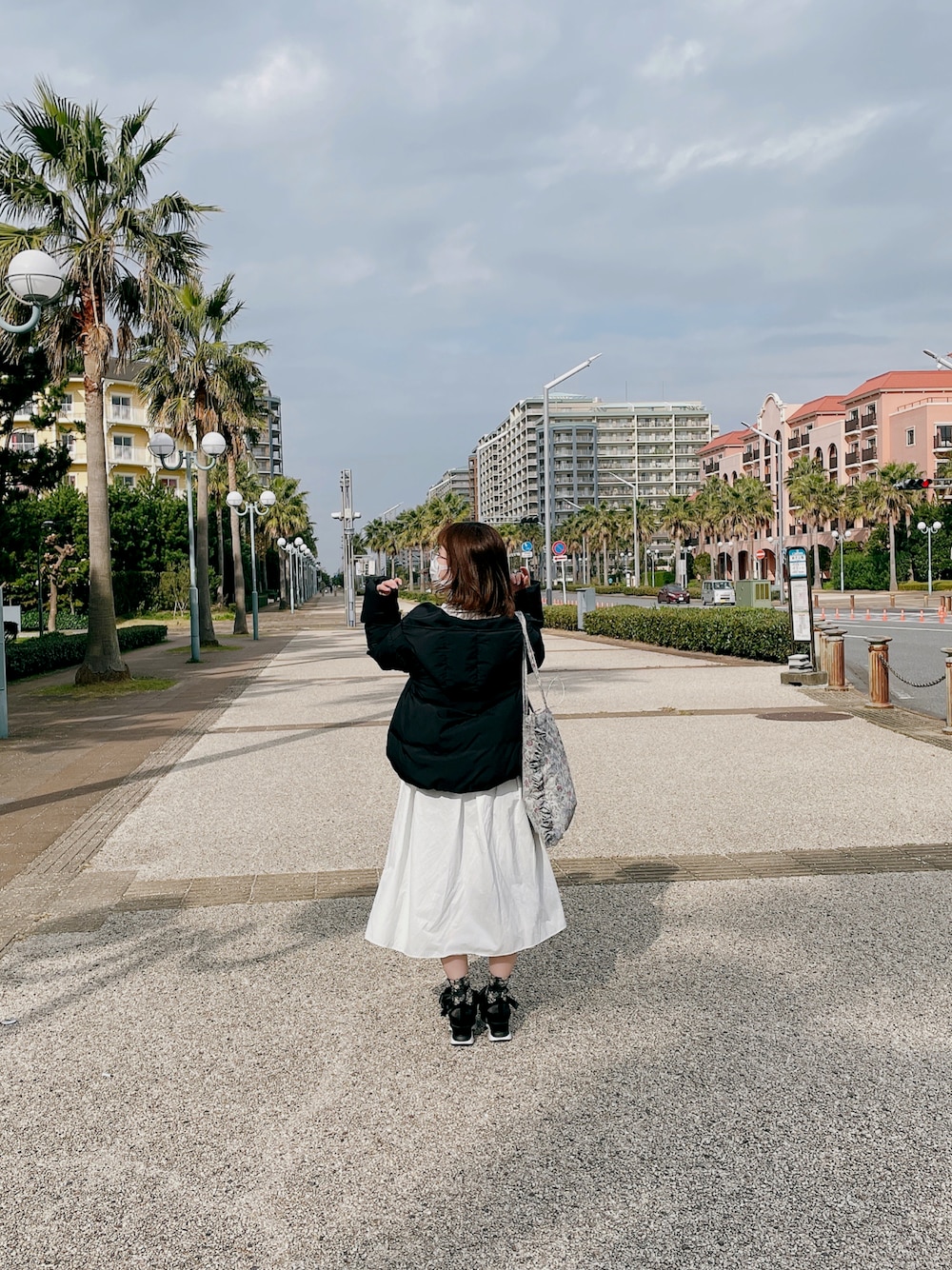 ブラック系のスニーカー、ホワイト系のワンピース、ブラック系のダウンジャケット/コートを着用したレディースの秋コーディネートの1枚目の写真