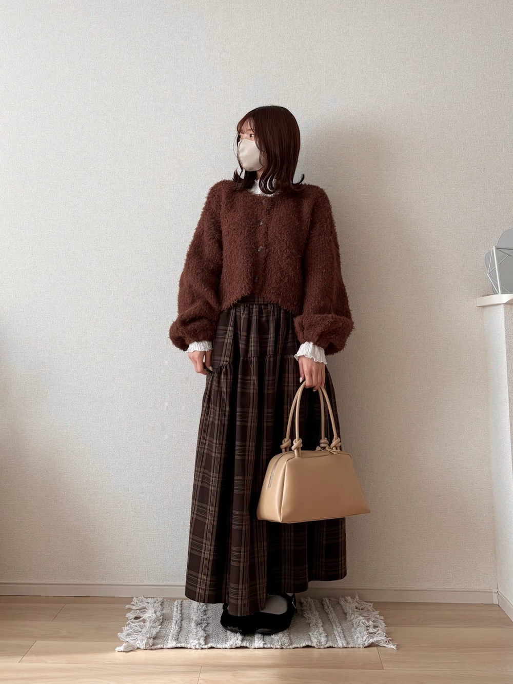 ベージュ系のボストンバッグ、ブラウン系のカーディガン/ボレロ、ホワイト系のTシャツ/カットソーを着用したレディースの冬コーディネートの1枚目の写真