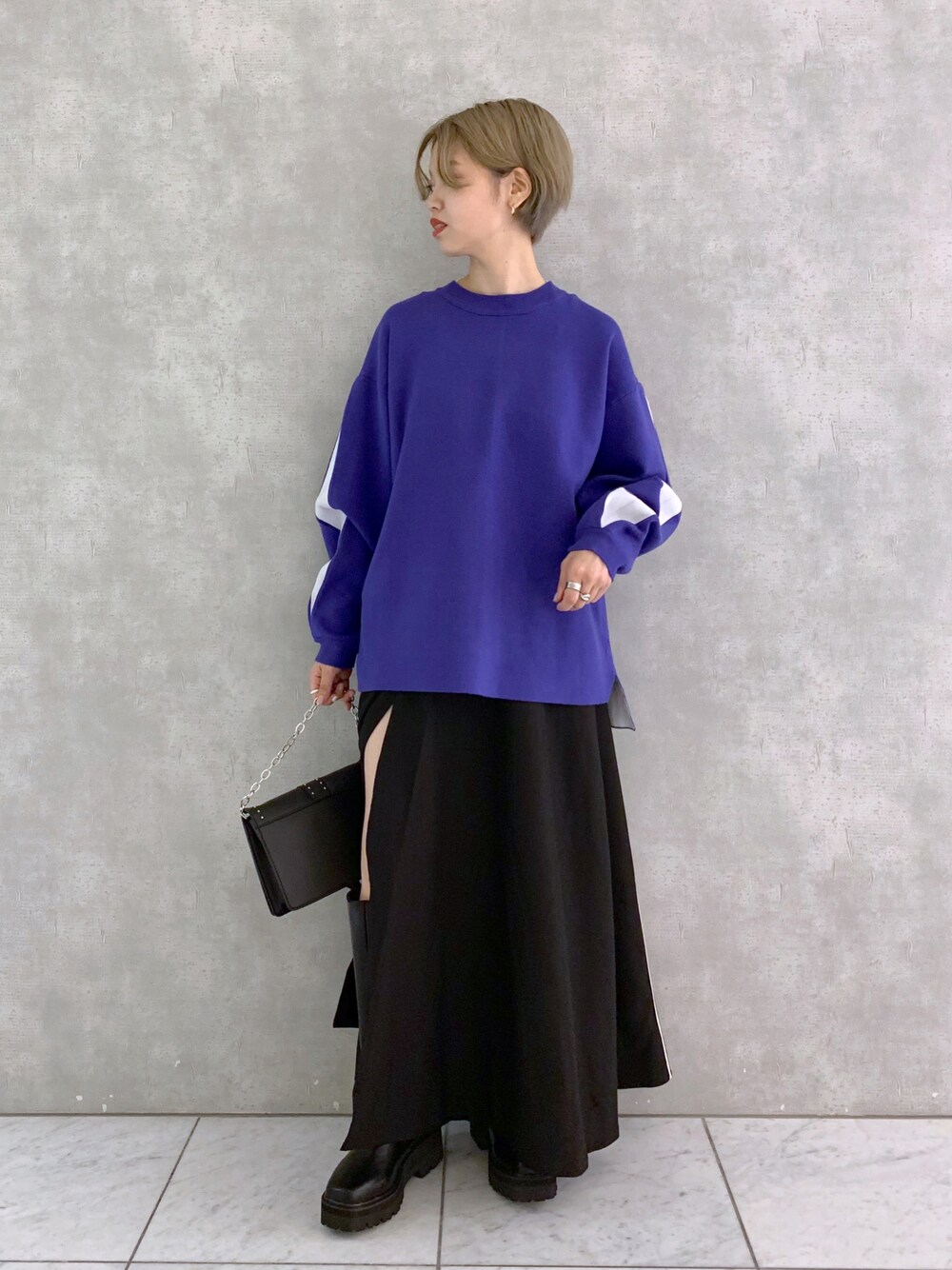 ブラック系のショルダーバッグ、ブラック系のスカート、ブラック系のブーツを着用したレディースの秋コーディネートの1枚目の写真