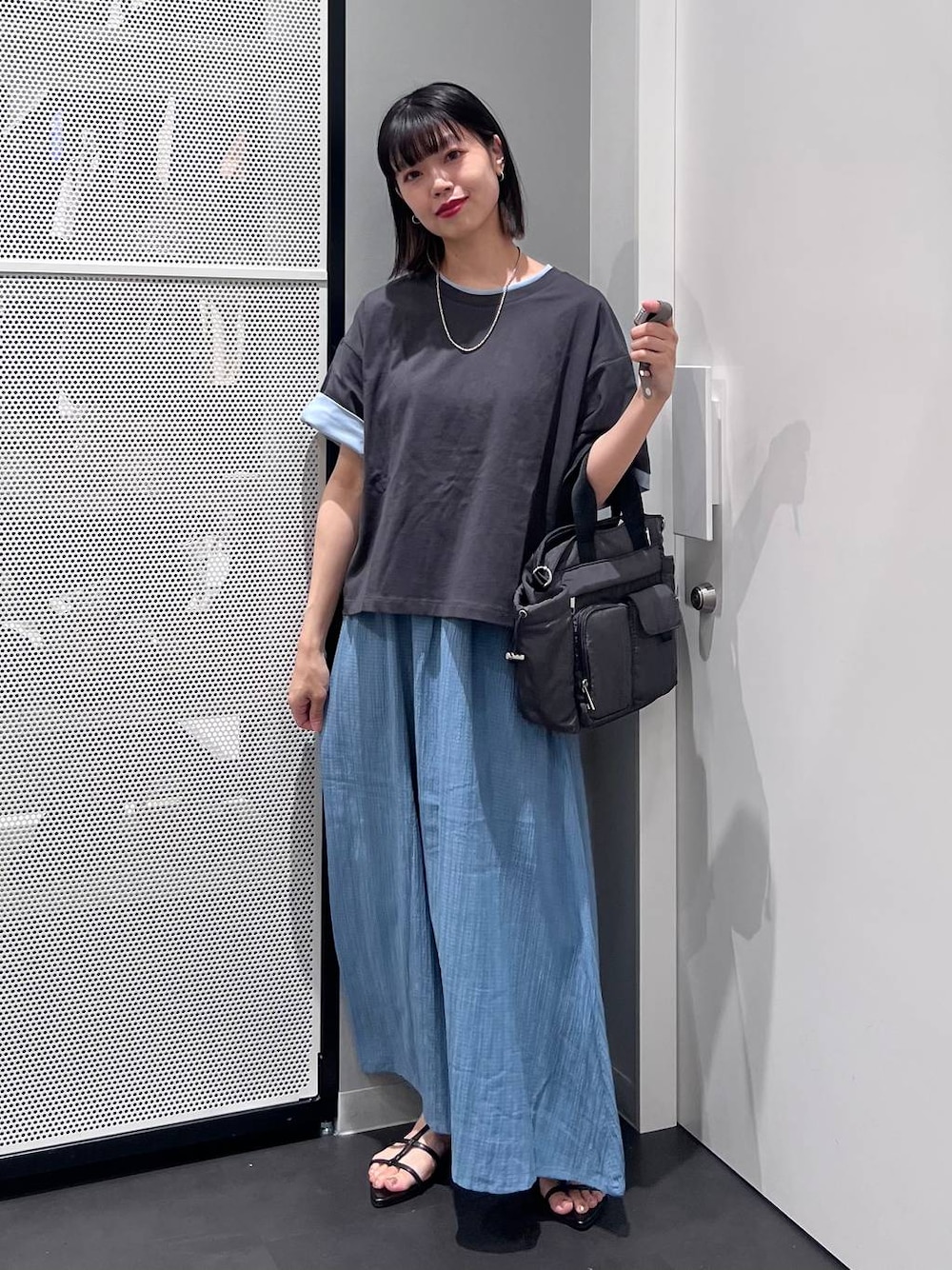 グレー系のTシャツ/カットソー、グレー系のトートバッグ、ブラック系のサンダルを着用したレディースの夏コーディネートの1枚目の写真