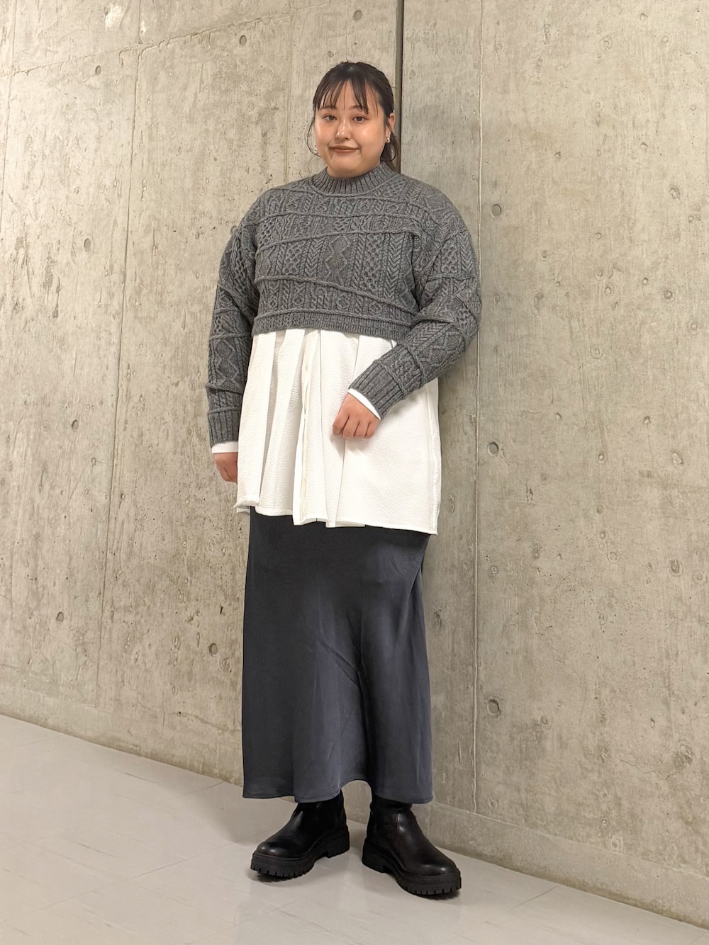 グレー系のニット/セーター、ホワイト系のシャツ/ブラウス、グリーン系のスカートを着用したレディースの冬コーディネートの1枚目の写真