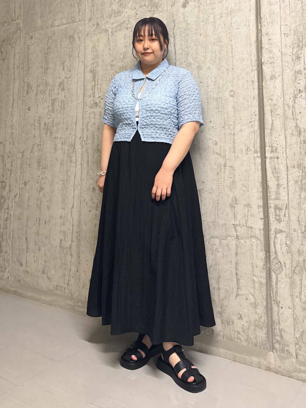 ブラック系のサンダル、ブラック系のスカート、ブルー系のシャツ/ブラウスを着用したレディースの春コーディネートの1枚目の写真