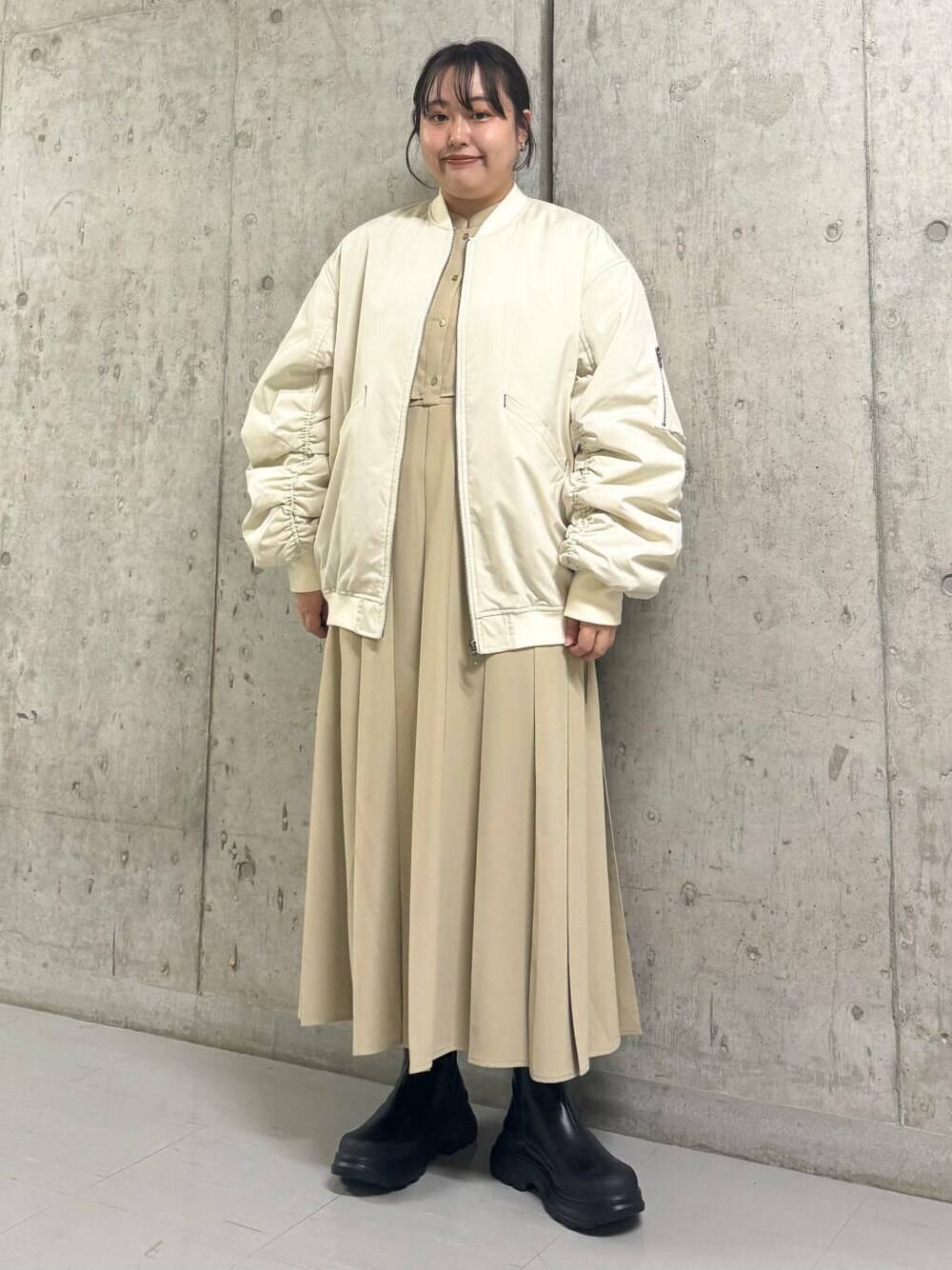 ブラック系のブーツ、ホワイト系のMA-1、ベージュ系のワンピースを着用したレディースの秋コーディネートの1枚目の写真