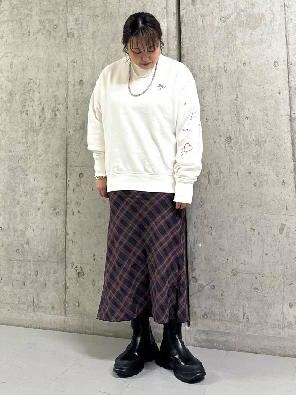 ブルー系のスカート、ブラック系のブーツ、ホワイト系のスウェットを着用したレディースの秋コーディネートの1枚目の写真
