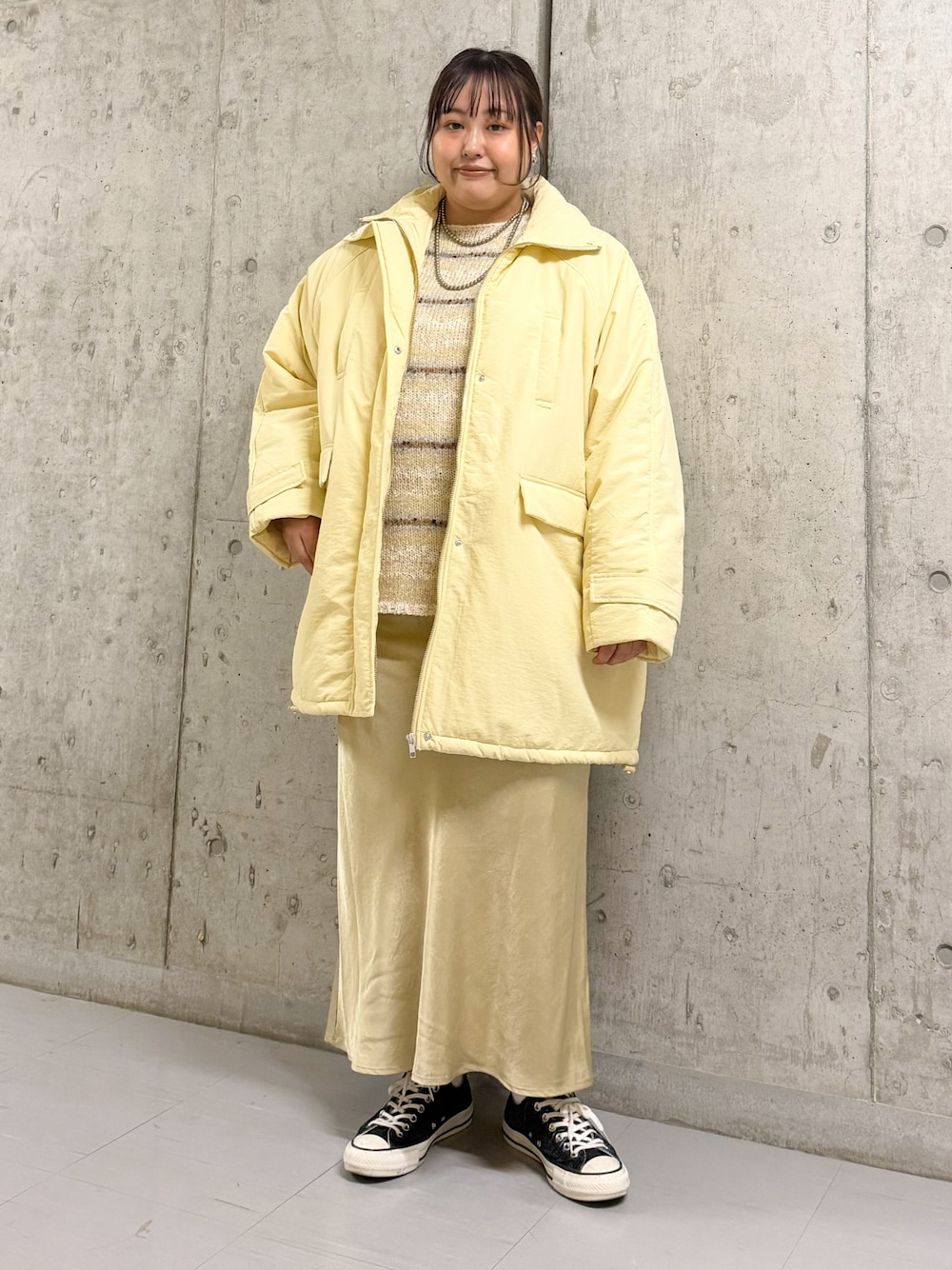 イエロー系のダウンジャケット/コート、ホワイト系のニット/セーター、パープル系のスカートを着用したレディースの秋コーディネートの1枚目の写真