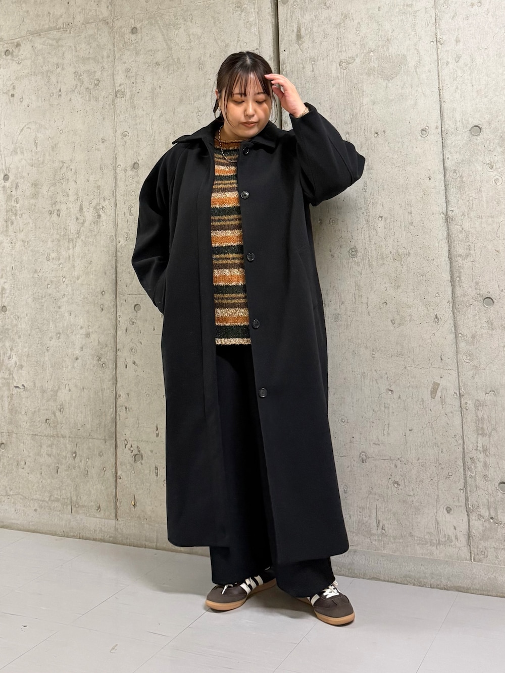 ブラック系のステンカラーコート、ブラウン系のニット/セーター、ブラック系のその他パンツを着用したレディースの冬コーディネートの1枚目の写真