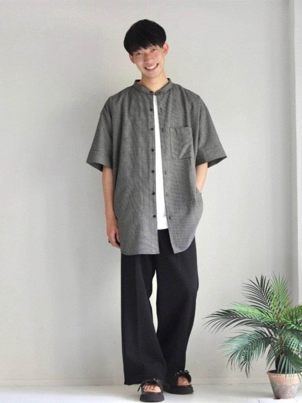 ホワイト系のTシャツ/カットソー、ブラック系のスラックス、ブラック系のサンダルを着用したメンズの夏コーディネートの1枚目の写真