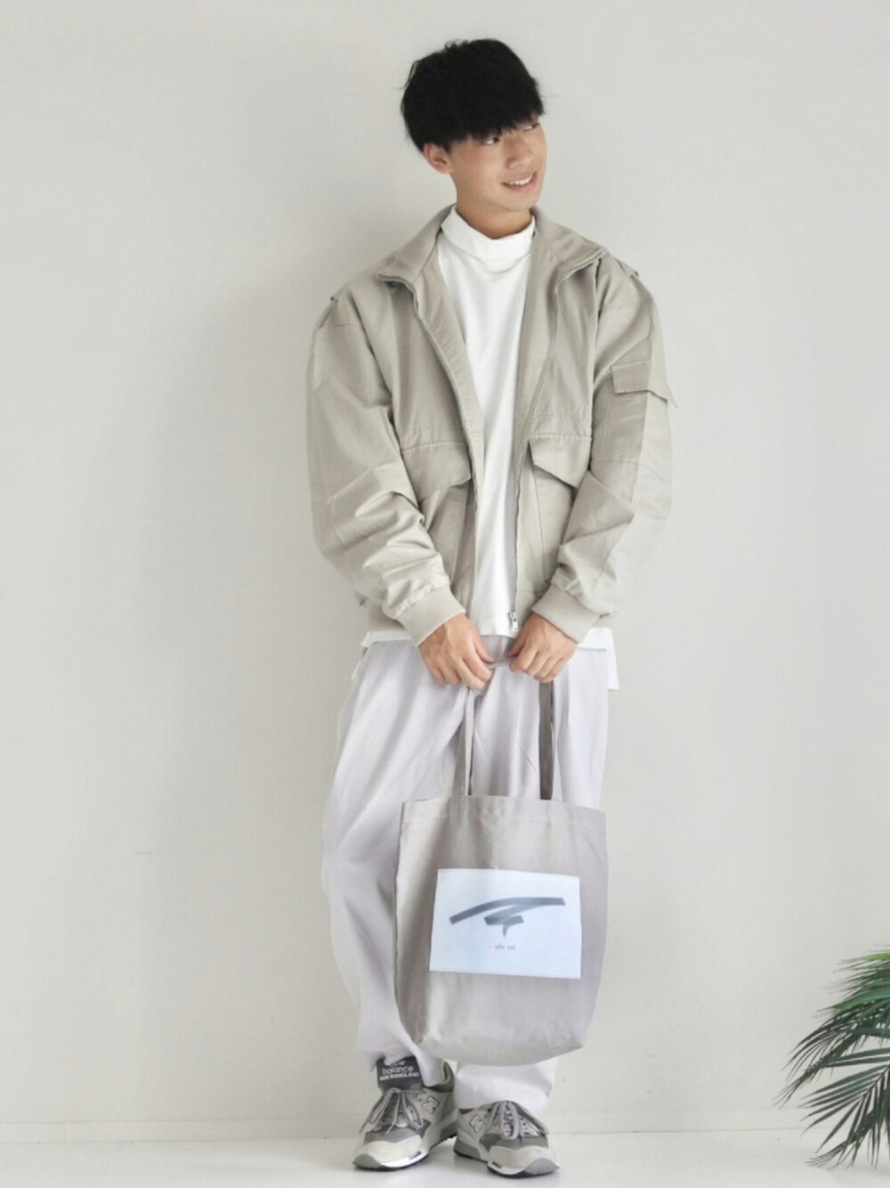 グレー系のトートバッグ、ホワイト系のTシャツ/カットソー、ベージュ系のMA-1を着用したメンズの秋コーディネートの1枚目の写真
