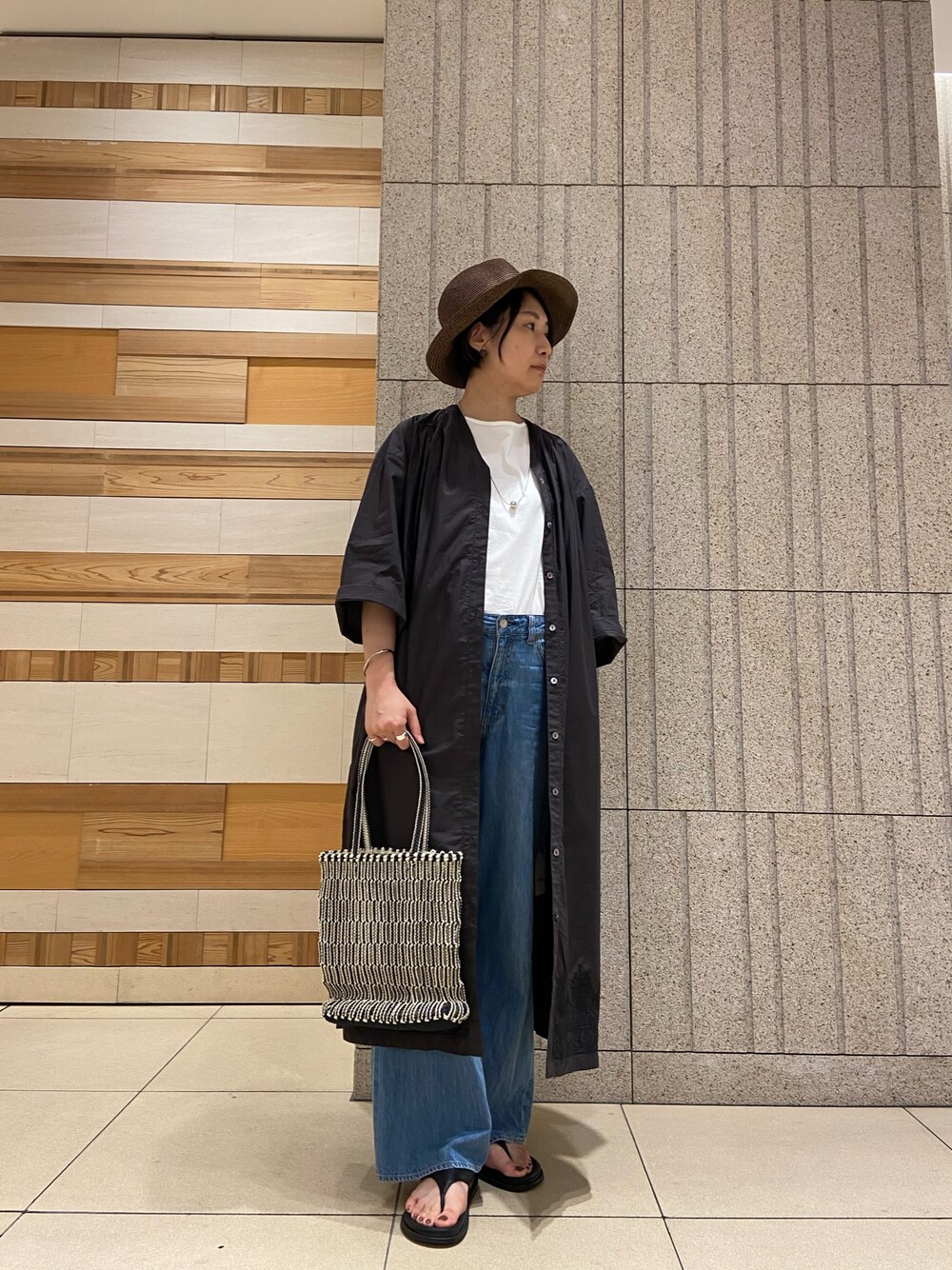 ブラック系のかごバッグ、ホワイト系のTシャツ/カットソー、ブラック系のサンダルを着用したレディースの夏コーディネートの1枚目の写真