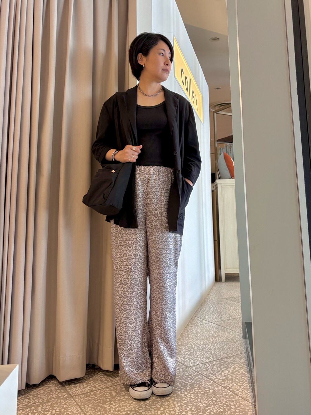 ブラック系のショルダーバッグ、ブラック系のテーラードジャケット、ブラック系のタンクトップを着用したレディースの春コーディネートの1枚目の写真