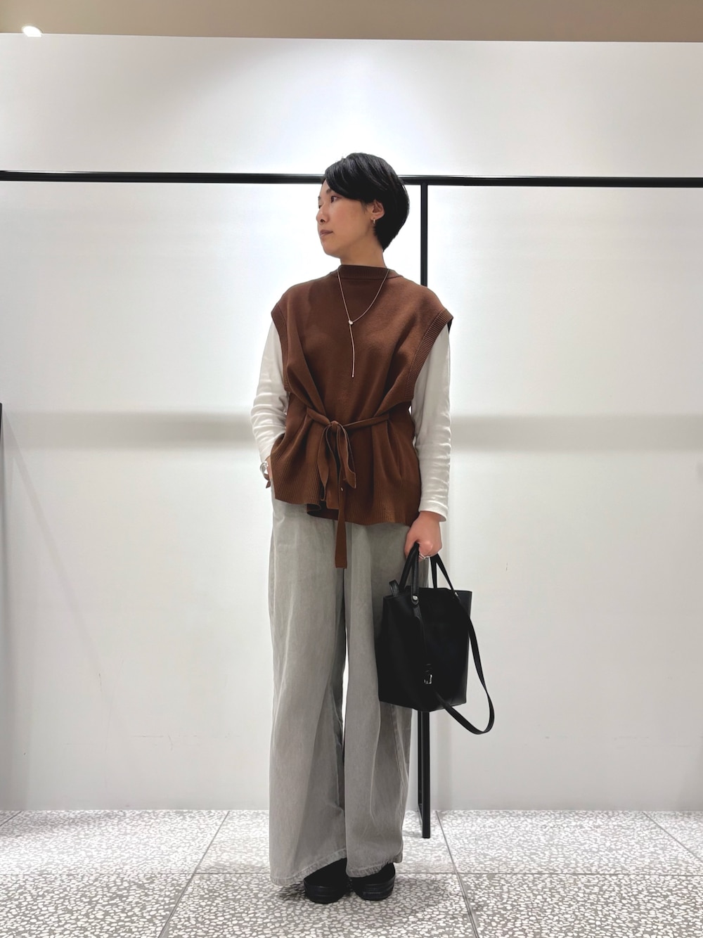 ブラウン系のベスト、ホワイト系のTシャツ/カットソー、グレー系のデニムパンツを着用したレディースの秋コーディネートの1枚目の写真