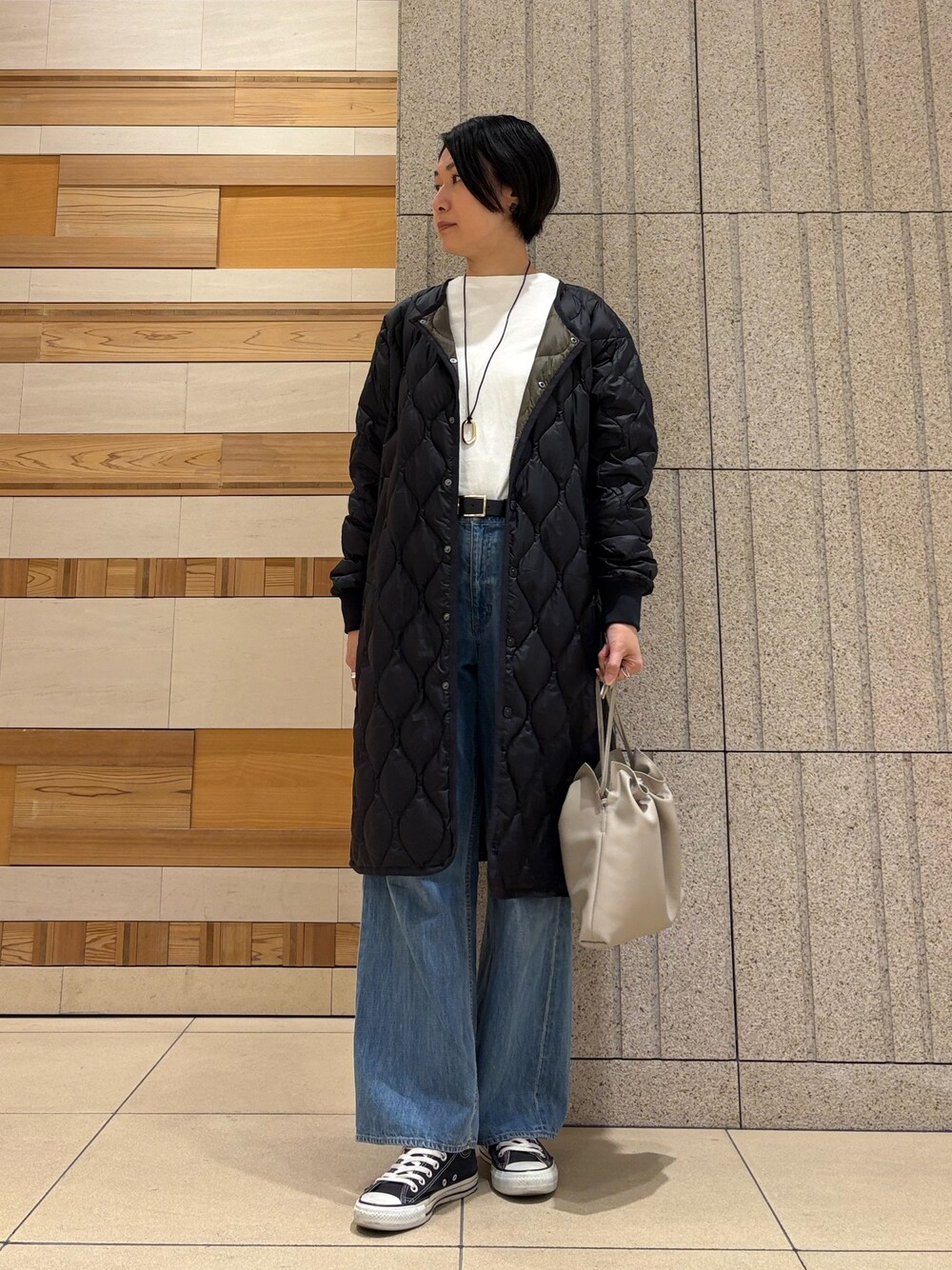 ベージュ系のショルダーバッグ、ブルー系のデニムパンツ、ブラック系のダウンジャケット/コートを着用したレディースの秋コーディネートの1枚目の写真