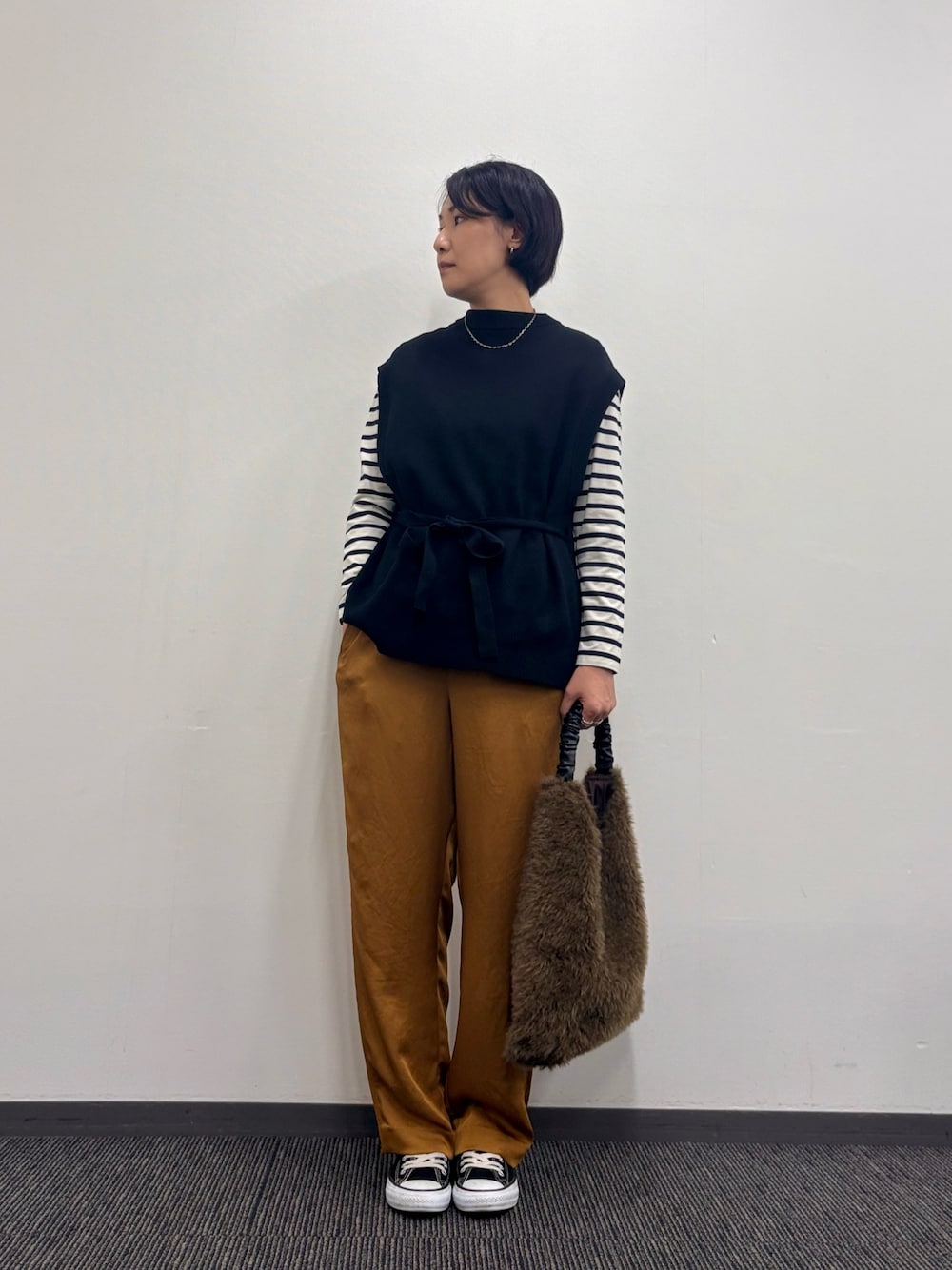 ブラック系のベスト、ブラウン系のその他パンツ、ブラウン系のトートバッグを着用したレディースの秋コーディネートの1枚目の写真