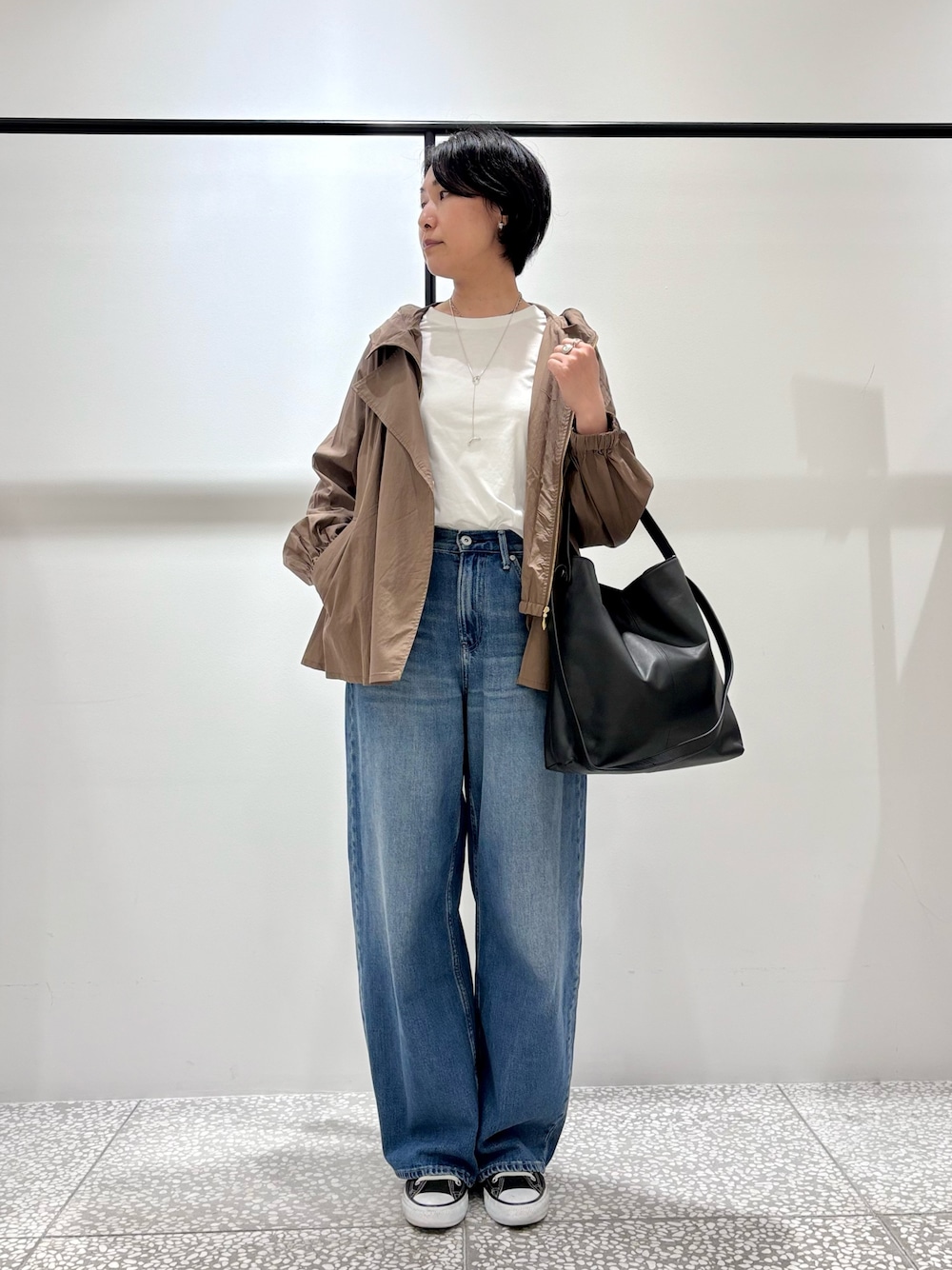 ブラック系のトートバッグ、ホワイト系のトレンチコート、ホワイト系のTシャツ/カットソーを着用したレディースの冬コーディネートの1枚目の写真