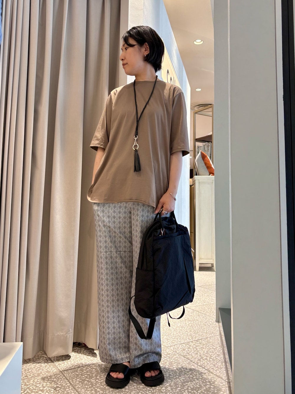 ブラウン系のTシャツ/カットソー、ブラック系のバックパック/リュック、ブラック系のその他パンツを着用したレディースの春コーディネートの1枚目の写真