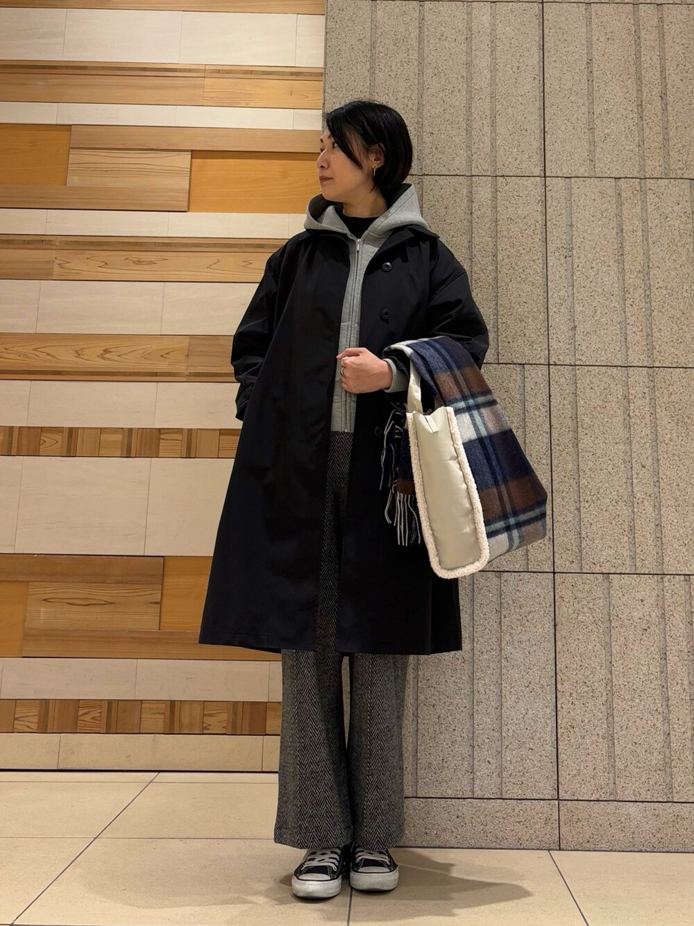 グレー系のパーカー、ブラック系のトレンチコート、ブラック系のその他パンツを着用したレディースの冬コーディネートの1枚目の写真