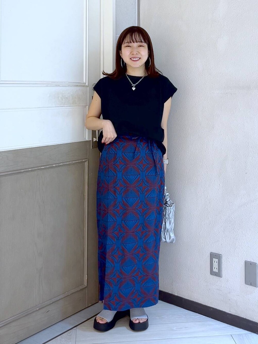シルバー系のサンダル、グレー系のショルダーバッグ、ブラック系のTシャツ/カットソーを着用したレディースの夏コーディネートの1枚目の写真