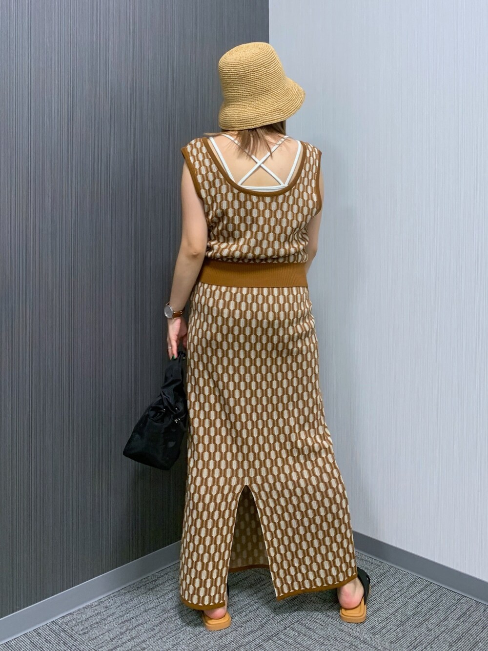 ブラウン系のベスト、ブラウン系のスカート、ブラック系のショルダーバッグを着用したレディースの夏コーディネートの3枚目の写真