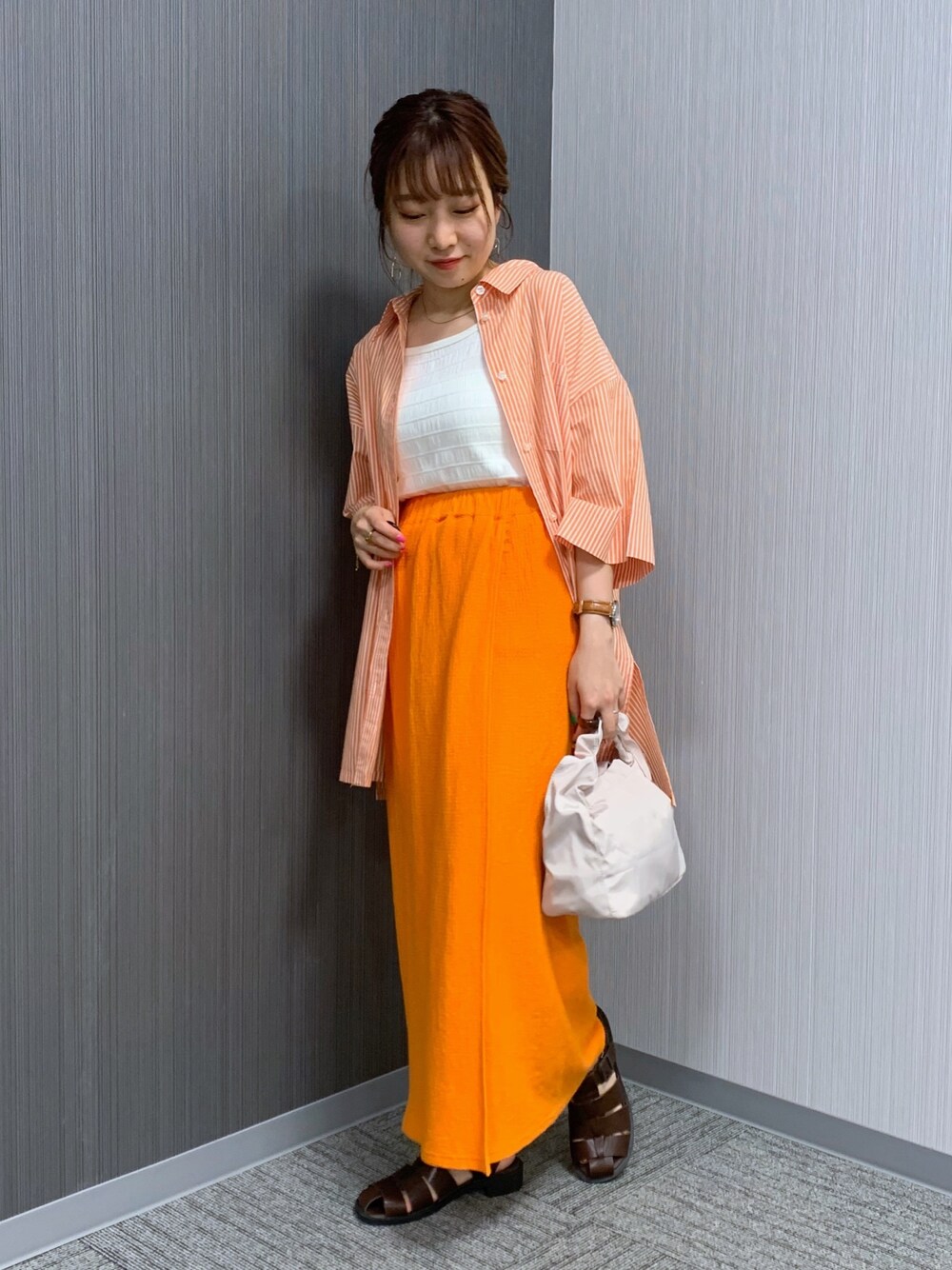オレンジ系のシャツ/ブラウス、オレンジ系のスカート、ホワイト系のショルダーバッグを着用したレディースの夏コーディネートの4枚目の写真